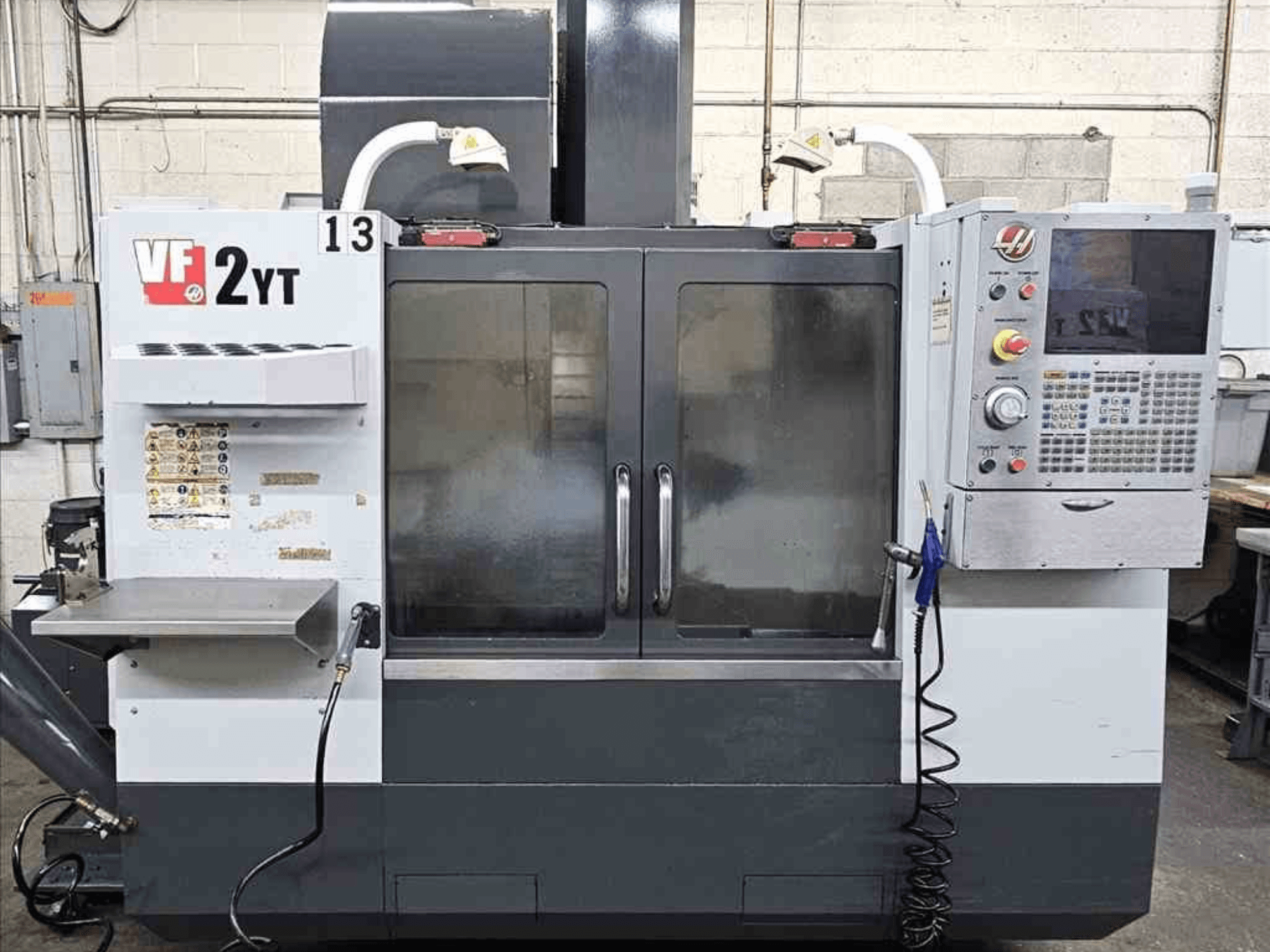 Vooraanzicht van een HAAS VF-2YT verticaal bewerkingscentrum, met het bedieningspaneel en de glazen deuren.