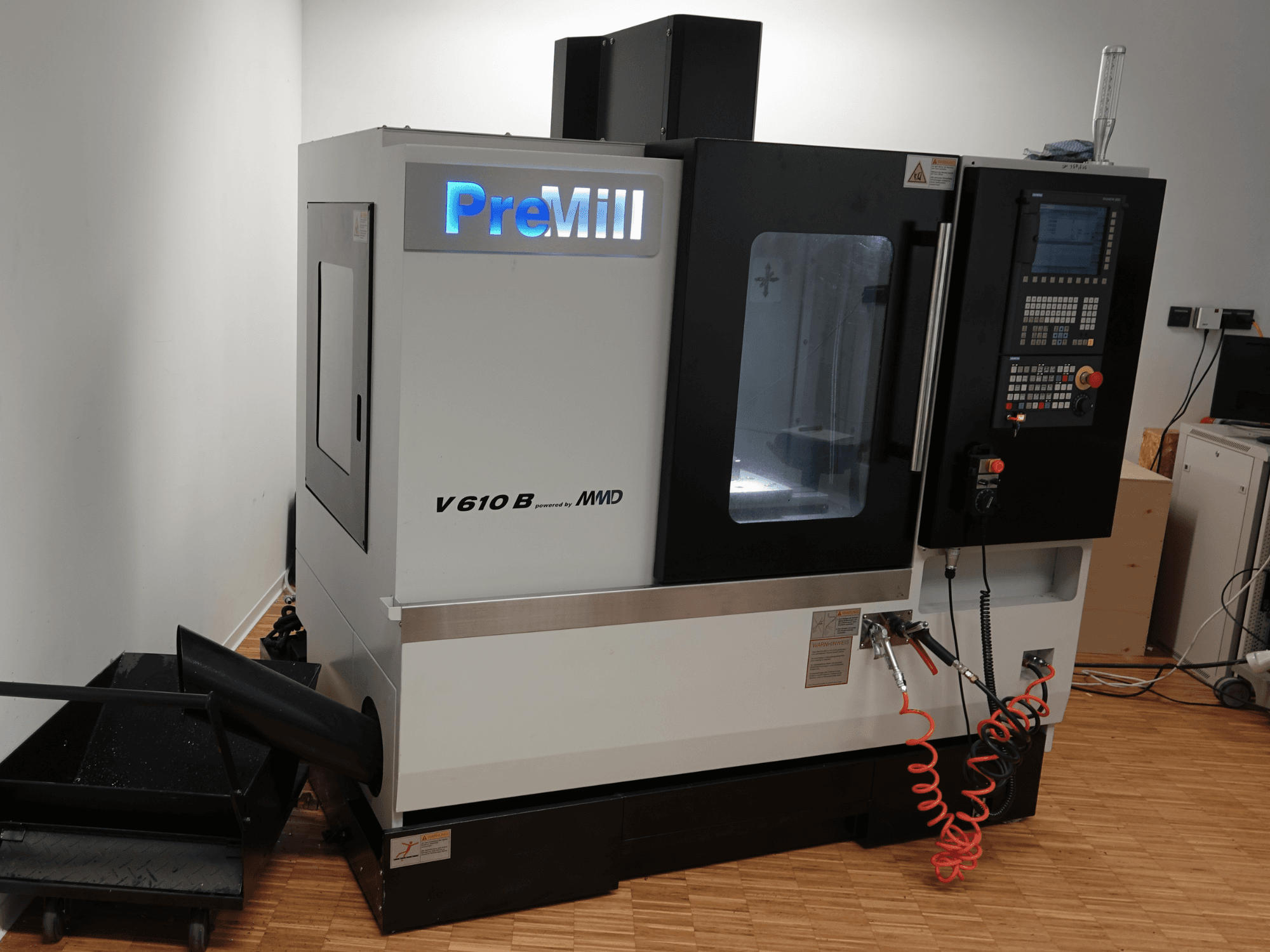 Verticaal bewerkingscentrum PreMill V 610 B, vooraanzicht, met bedieningspaneel, koelsysteem en aangesloten luchtslangen.