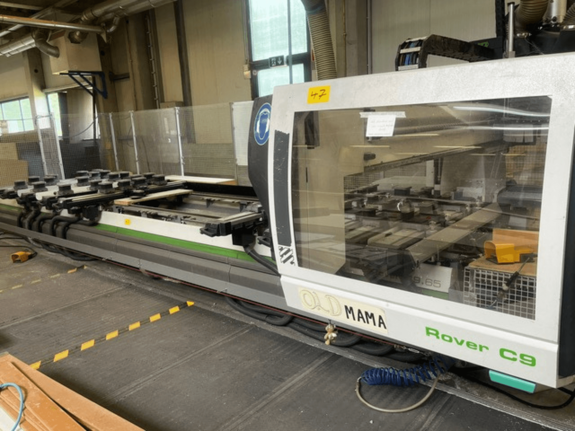 BIESSE Rover C 9.65 CNC bovenfrees in een werkplaats, zijaanzicht met bedieningspaneel en werktafel met klemmen.