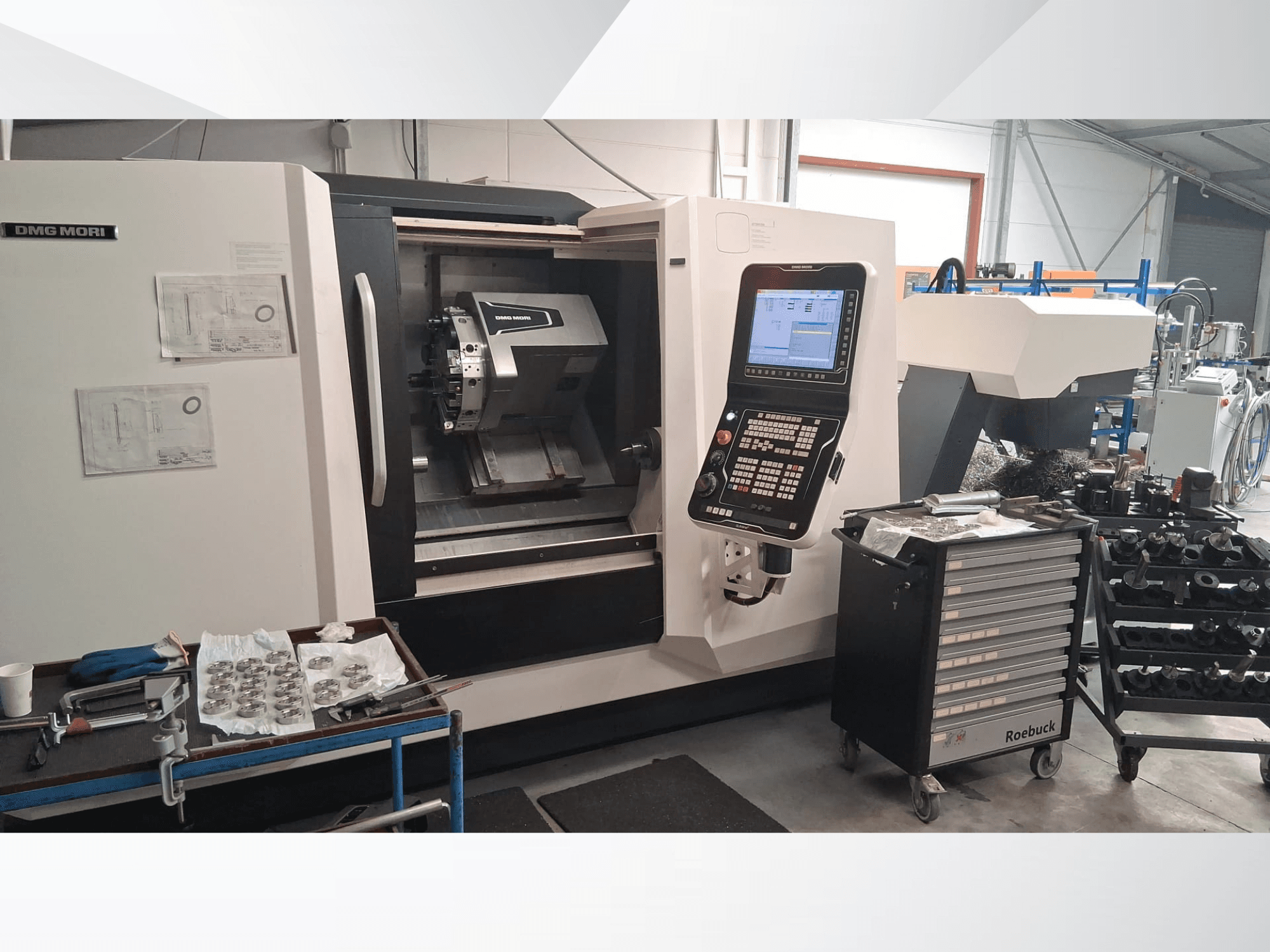 DMG MORI CLX450 horizontale draaimachine in vooraanzicht, met bedieningspaneel, werkgebied, gereedschappen en metalen onderdelen.