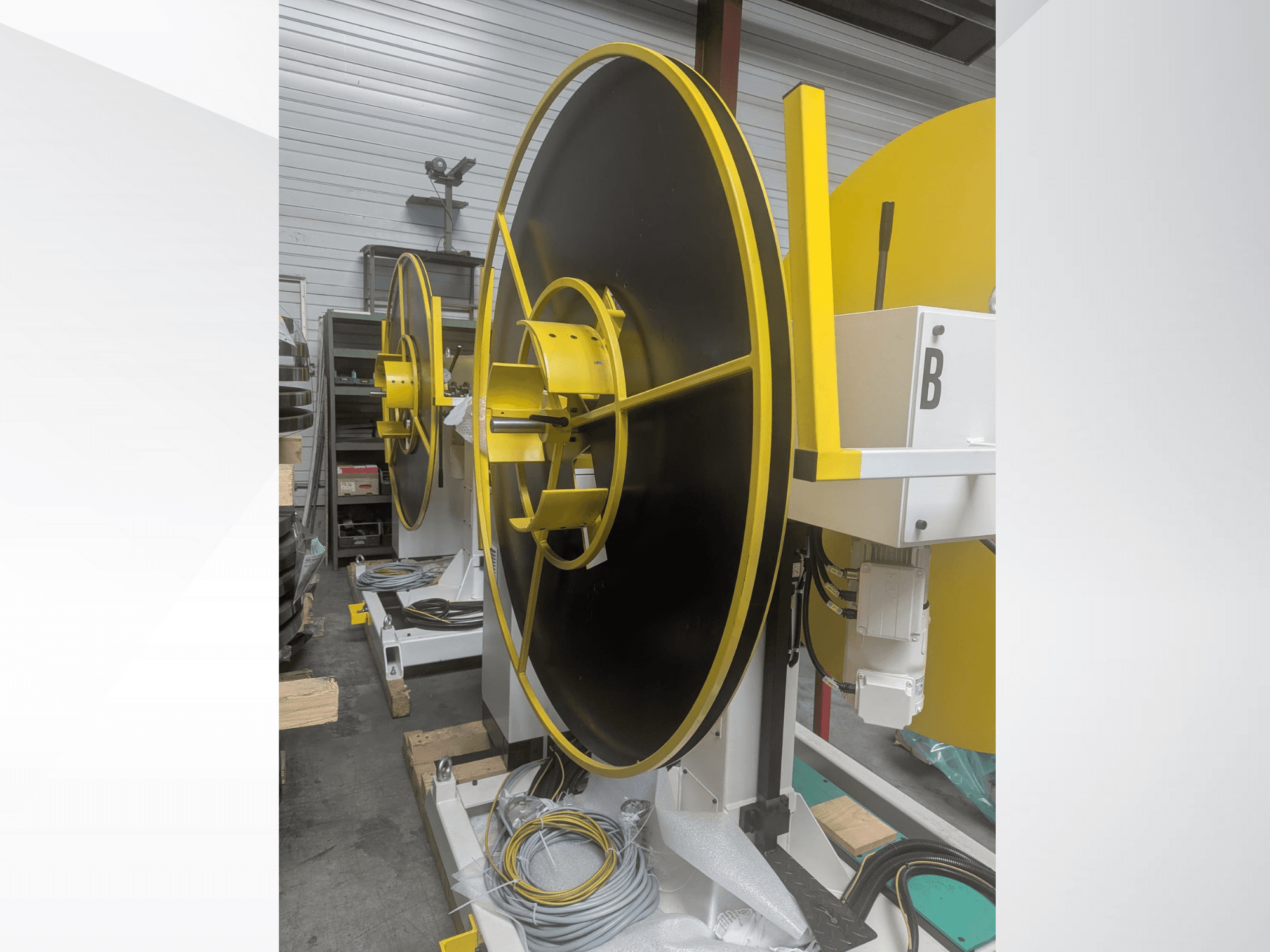 Grote industriële spoel, model XYZ, met een zwart oppervlak en gele accenten, zijaanzicht, met elektrische aansluitingen.