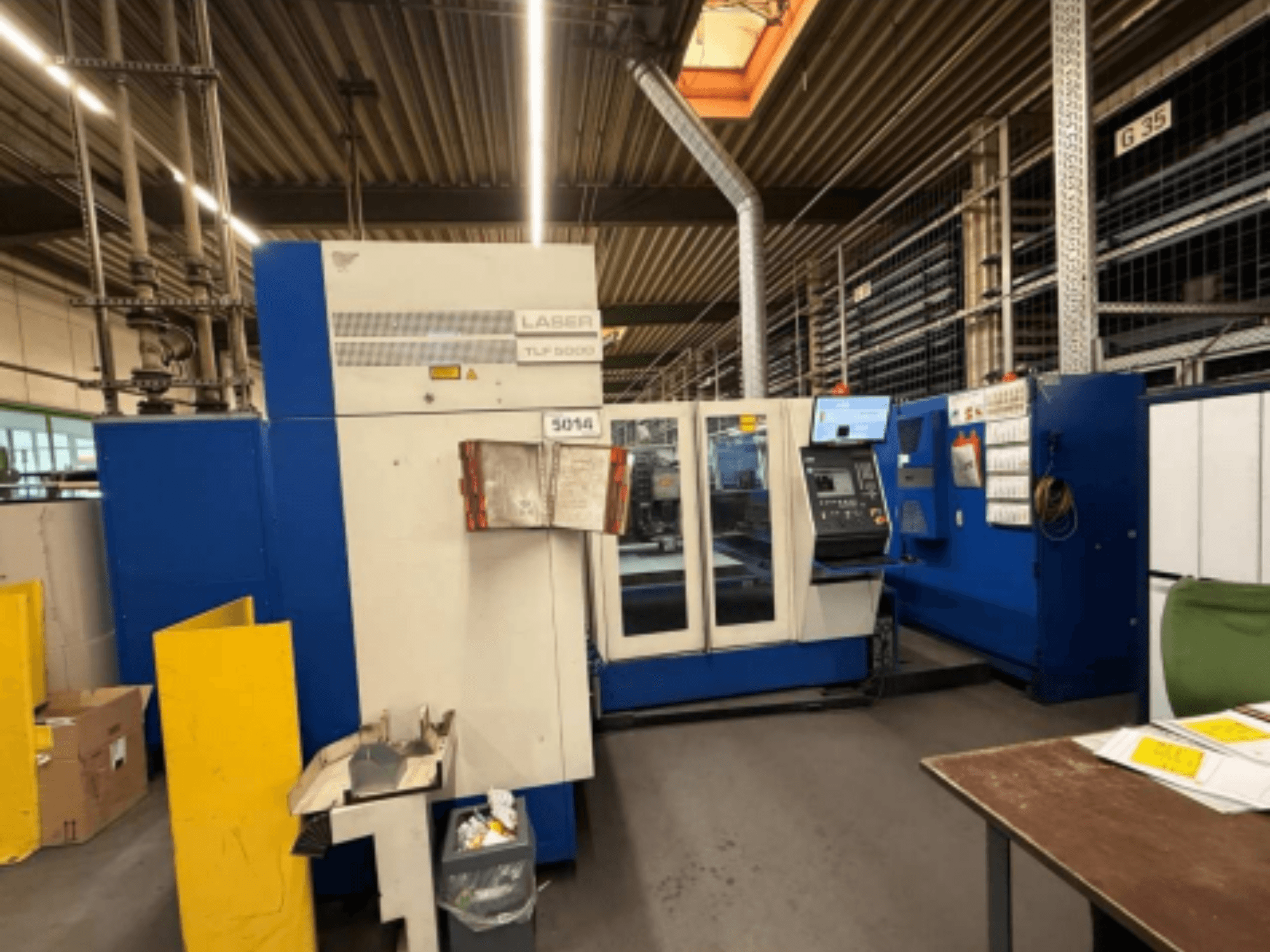 Vooraanzicht van de TRUMPF Trumatic L 3050 CO2 lasersnijmachine, met het bedieningspaneel en de bedieningsfuncties in een werkplaats.