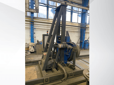 Industriële machine met een blauwe motor en metalen frame, gezien vanaf de voorkant in een werkplaats.