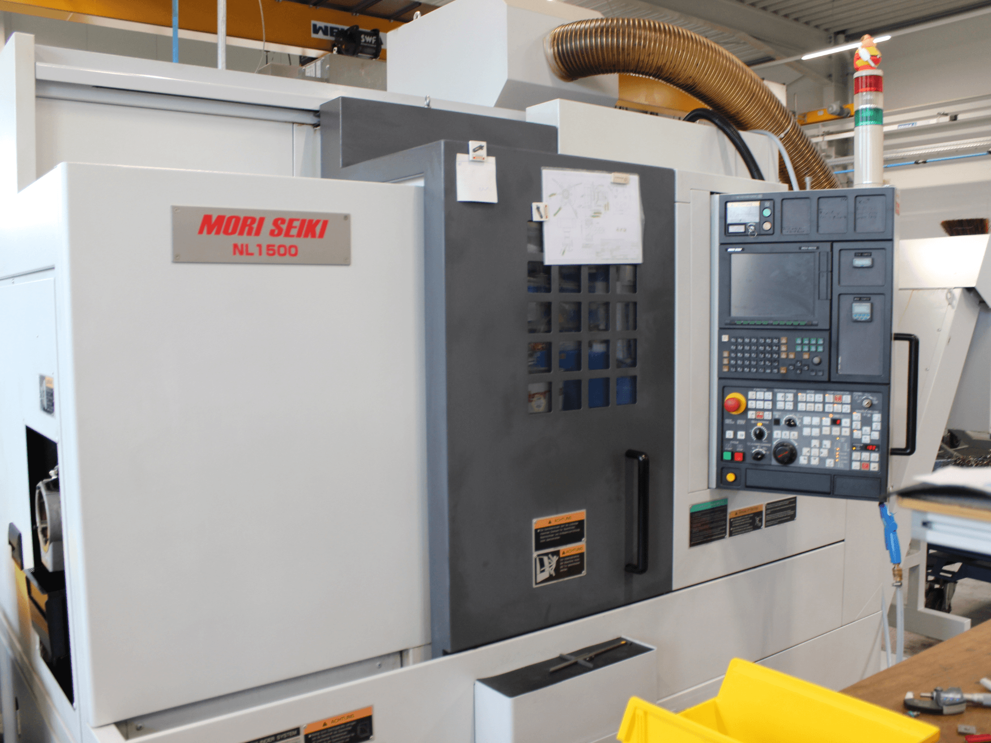 MORI SEIKI NL 1500 SY draai-freescentrum in zijaanzicht, met bedieningspaneel, veiligheidslabels en koelsysteem.