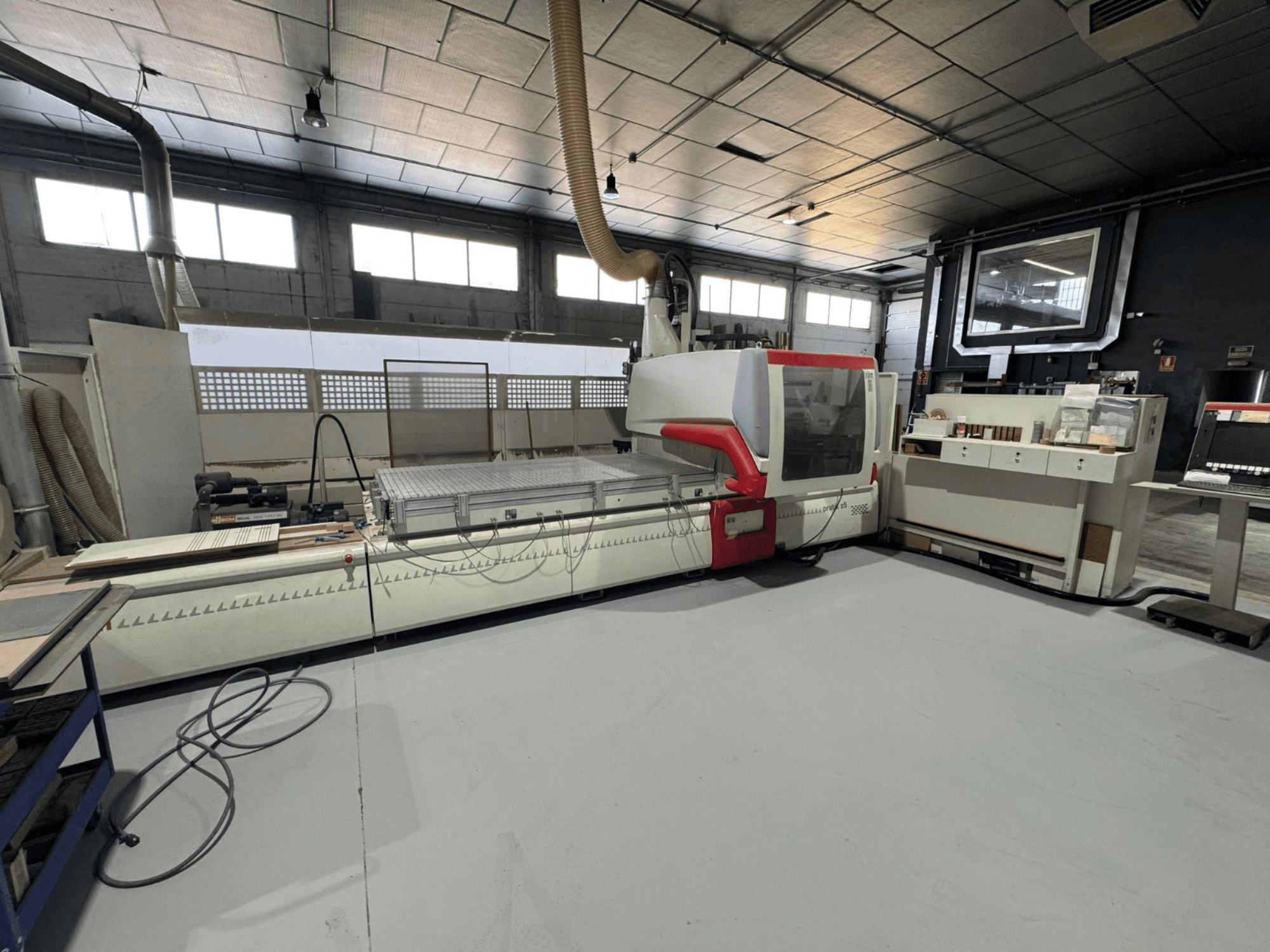 CNC machine in een werkplaats, vooraanzicht met rode accenten, uitgerust met bedieningspaneel en werkoppervlak, voor precisiesnijwerk.