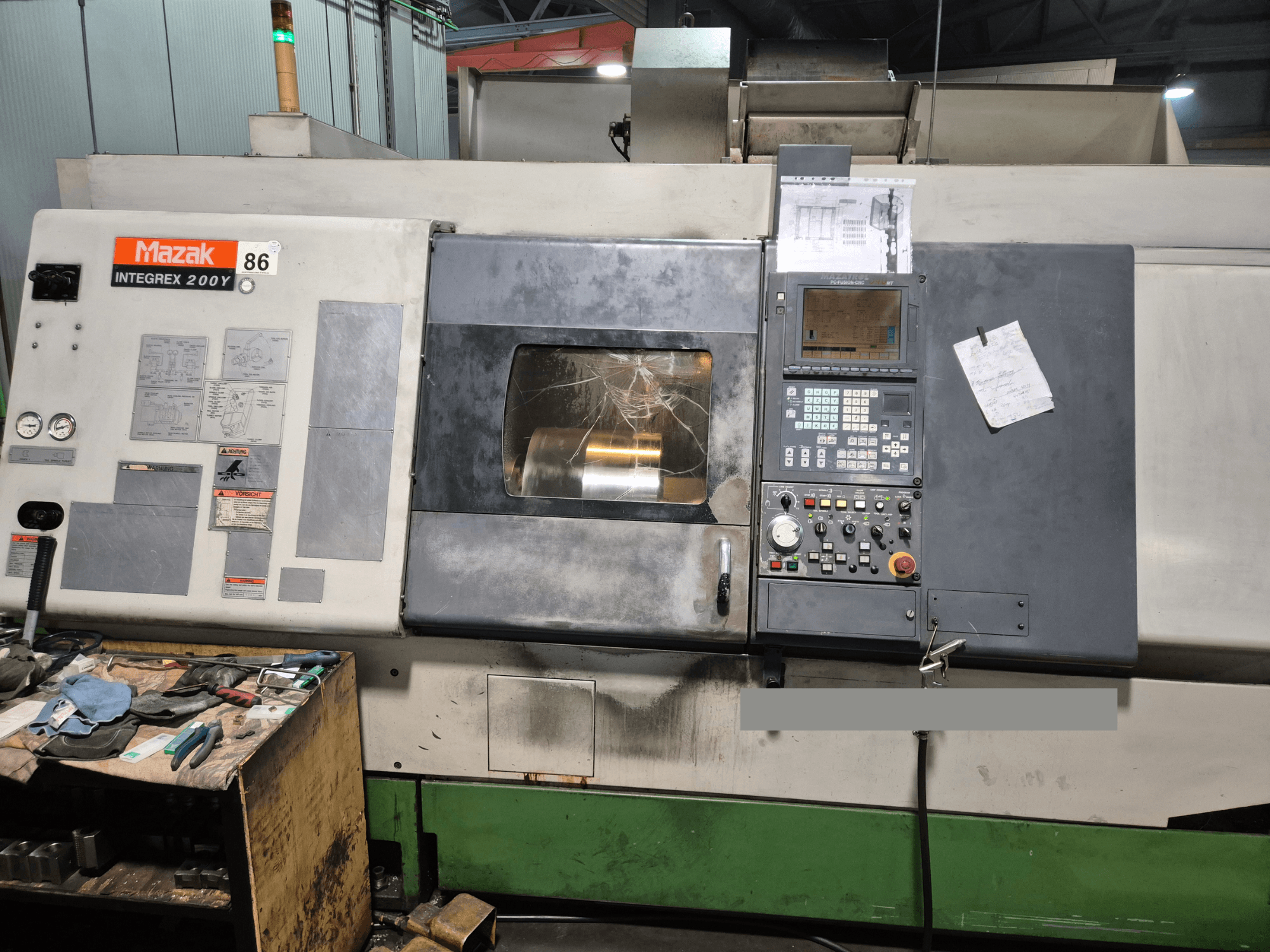 Mazak Integrex 200Y draaibank, vooraanzicht, met bedieningspaneel en gereedschappen op een werkbank. Zichtbare meters en display.