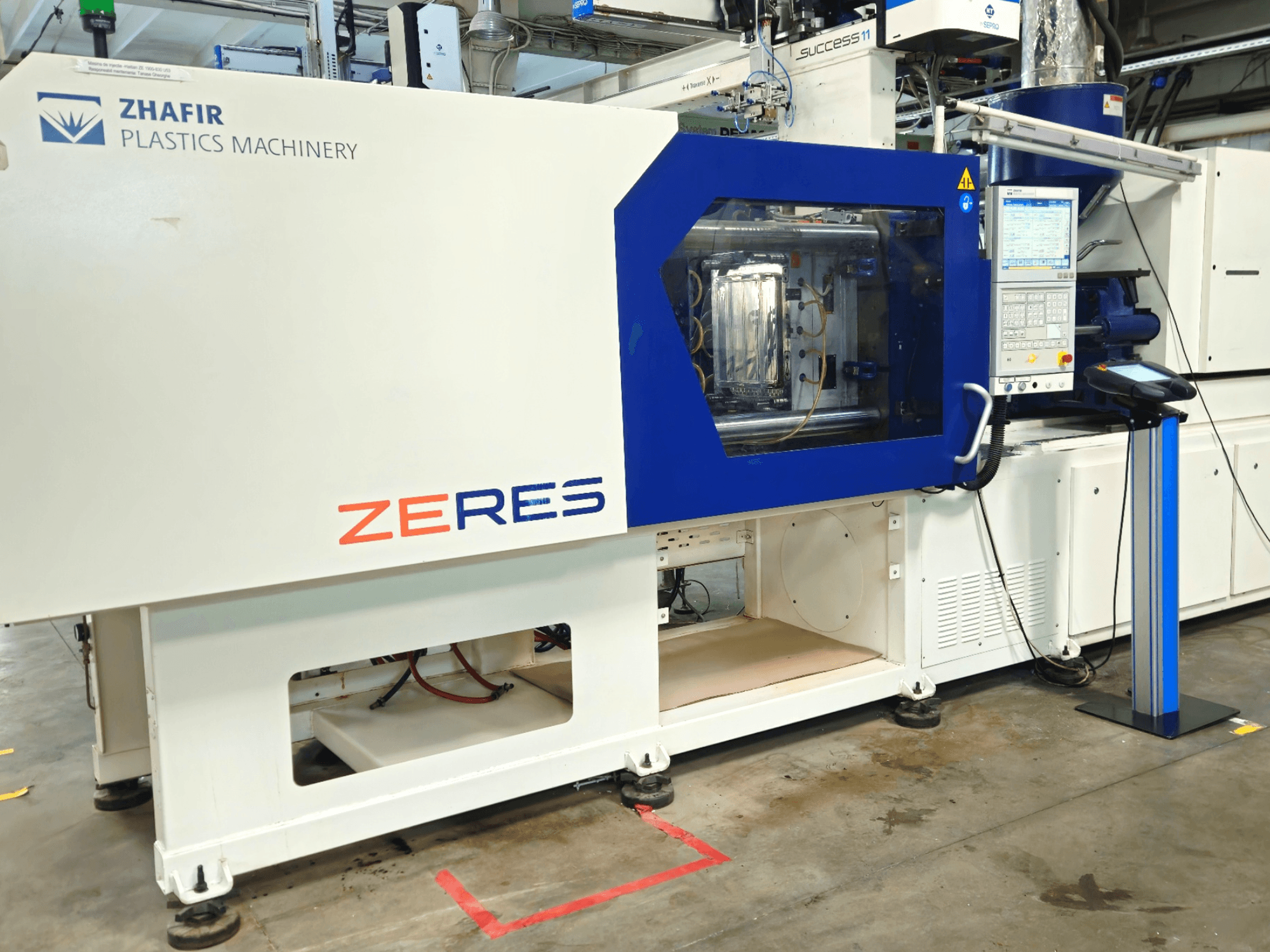 Zhafir Zeres spuitgietmachine in vooraanzicht, met bedieningspaneel en transparant spuitgietgedeelte.
