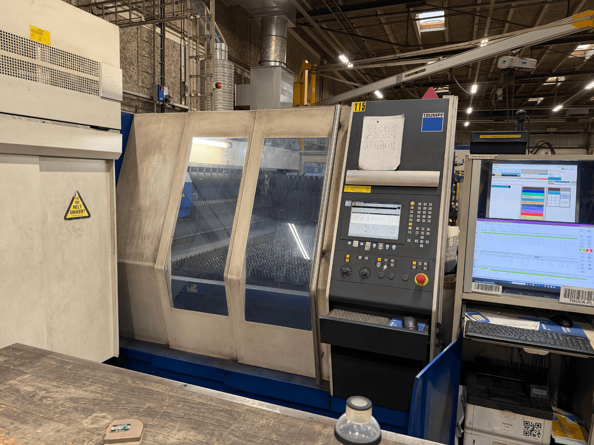 Vooraanzicht van een industriële lasermachine van Trumpf met bedieningspaneel en digitale displays, opgesteld in een fabrieksomgeving.