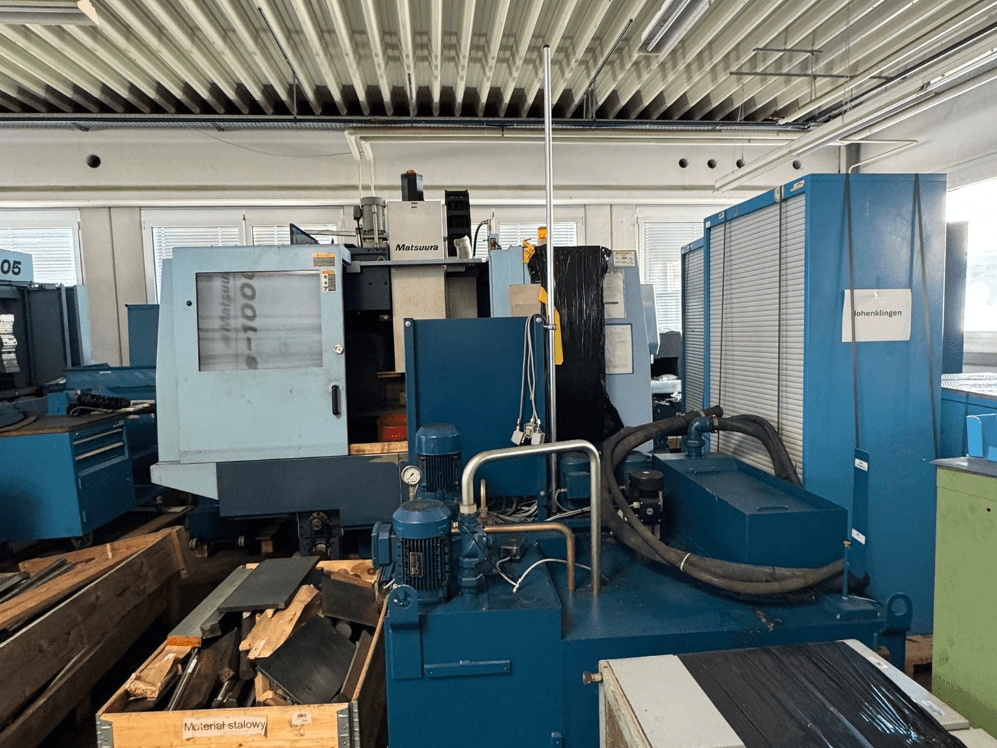 Vooraanzicht van het verticale bewerkingscentrum Matsuura Vplus 1000/40, met daarop de bedieningselementen, motoren en de omringende werkplaatsomgeving.
