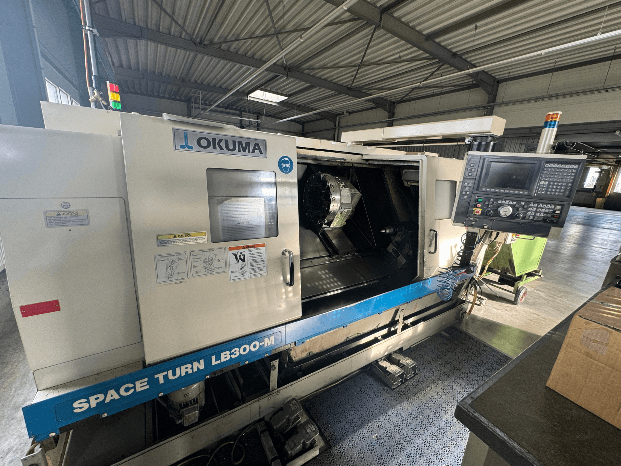 Okuma Space Turn LB300-M CNC draaibank in vooraanzicht, met bedieningspaneel en open deur die het bewerkingsgebied onthult.