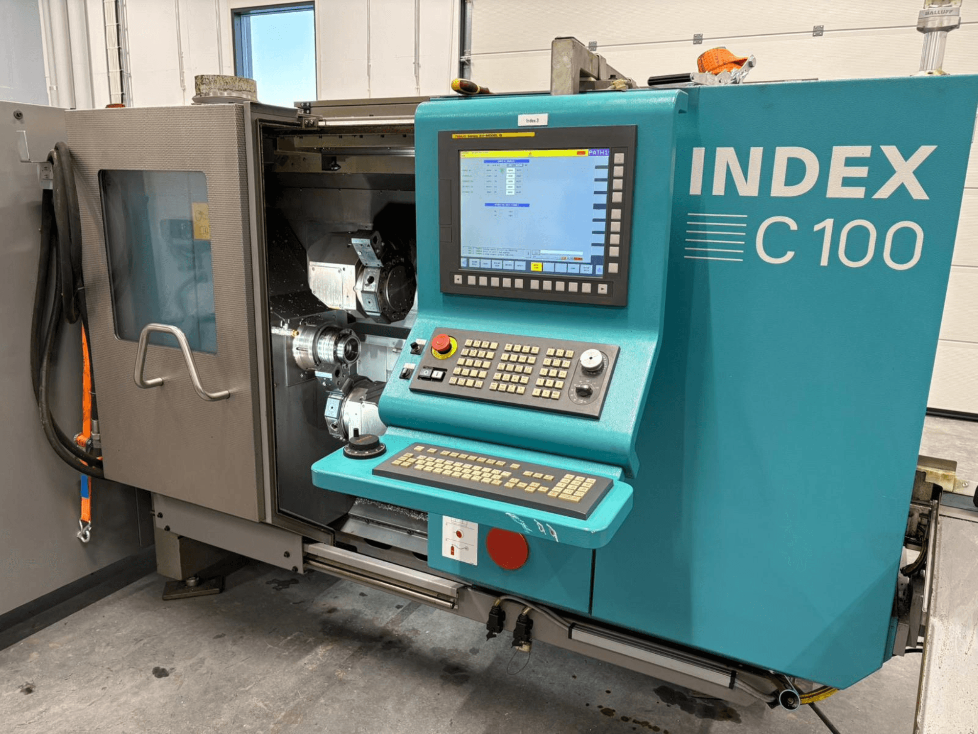 Vooraanzicht van Index C100 Zwitserse draaimachine met bedieningspaneel en open behuizing waarop de interne componenten te zien zijn.