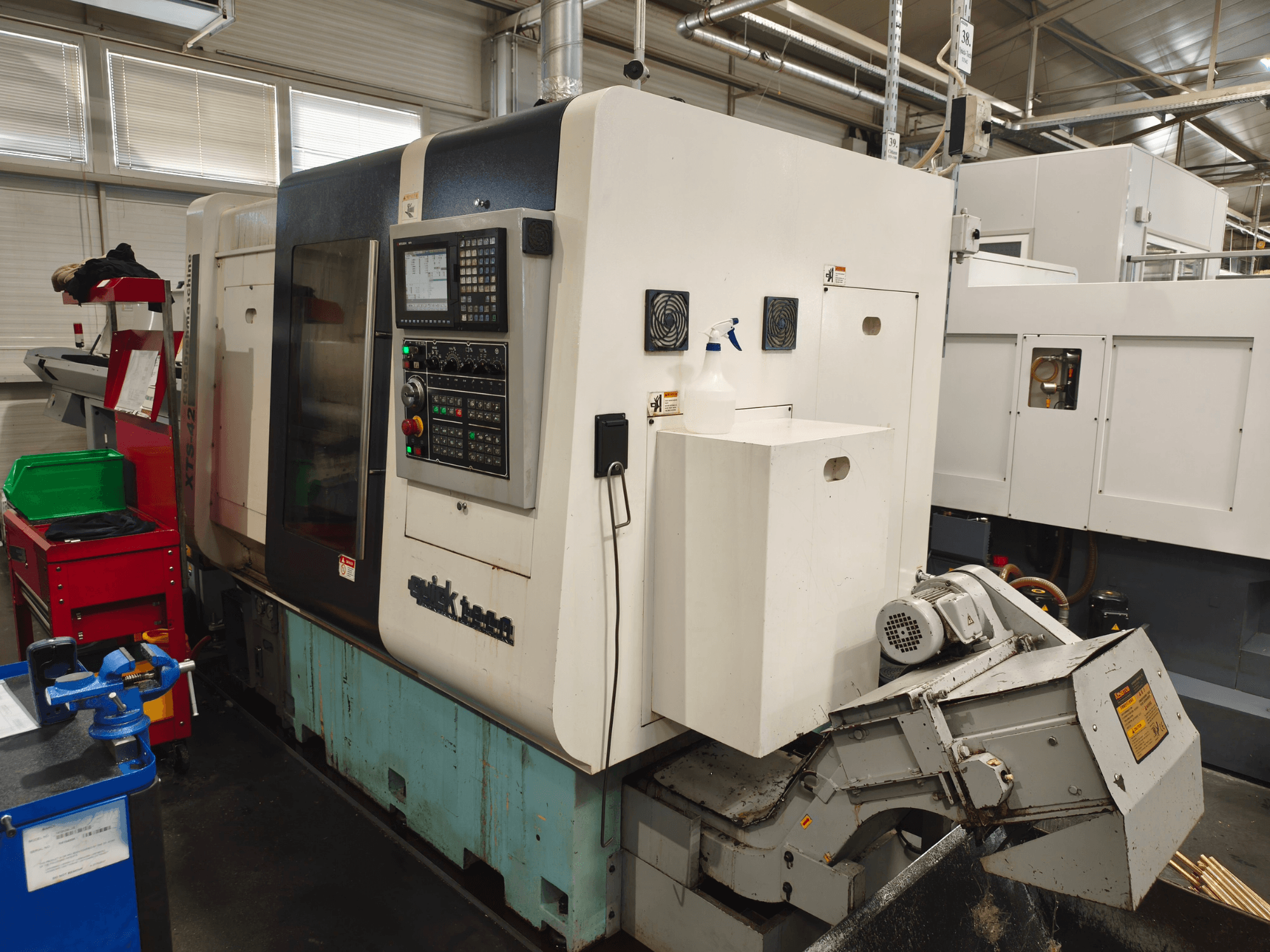 Vooraanzicht van de Quick-Tech XTS-42 horizontale draaibank, met bedieningspaneel en koelvloeistofreservoir.