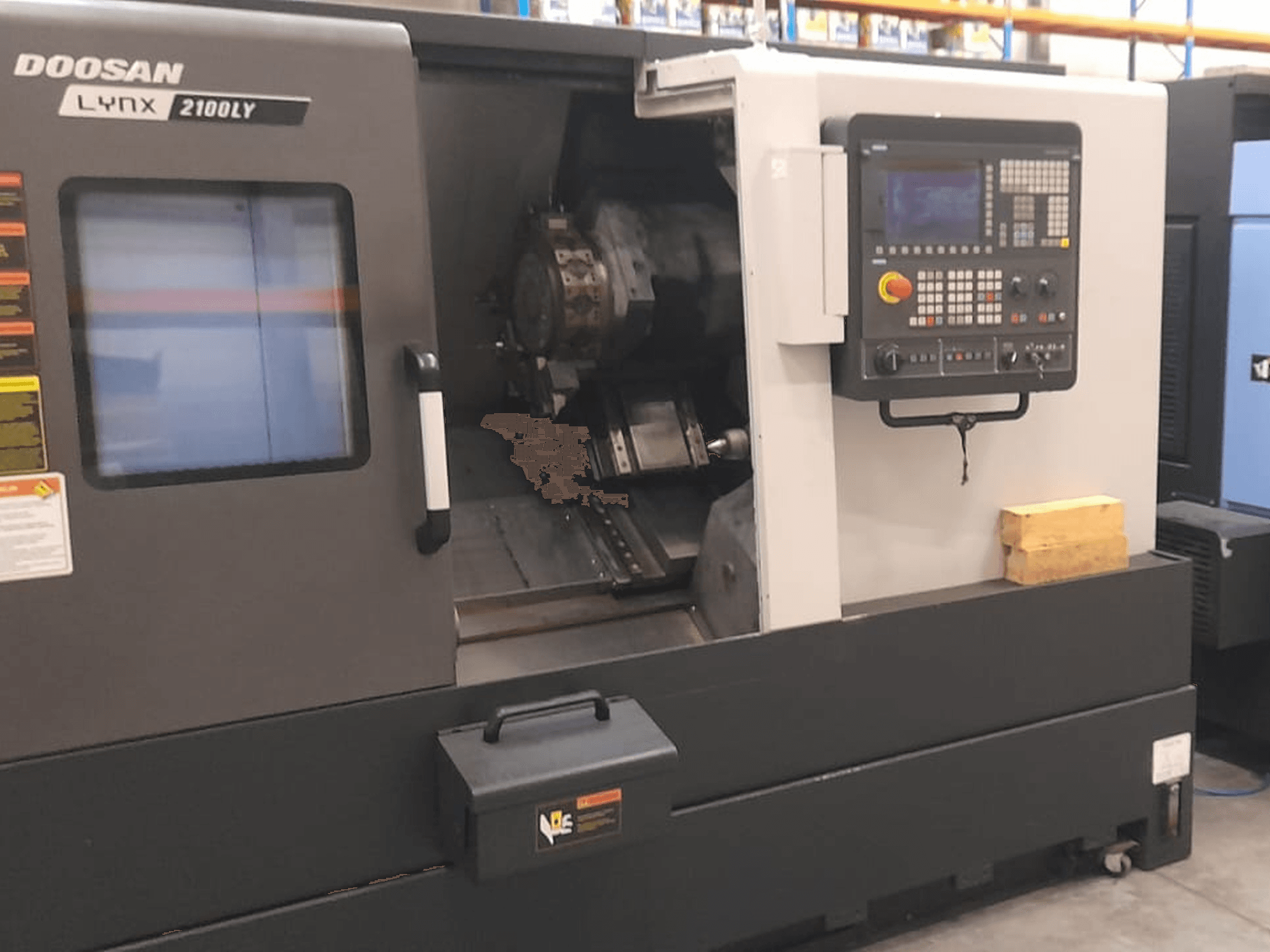 Doosan Lynx 2100LY CNC draaibank, vooraanzicht met bedieningspaneel, gereedschaphouder en werkruimte aan de binnenkant; technische labels zichtbaar.