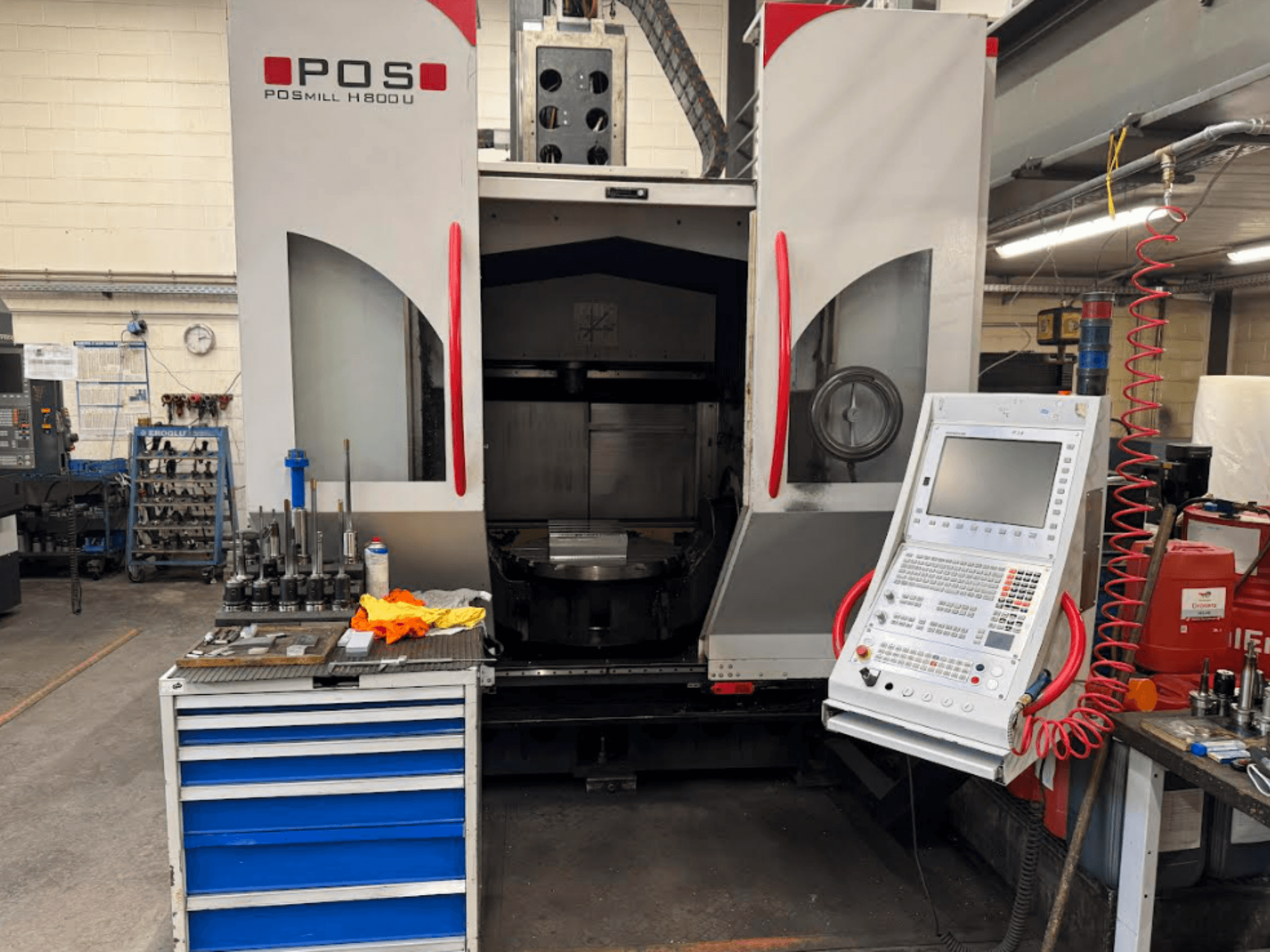 POSMILL H800 U CNC machine gezien vanaf de voorkant, met het bedieningspaneel en het werkgebied met gereedschappen en apparatuur in de buurt.