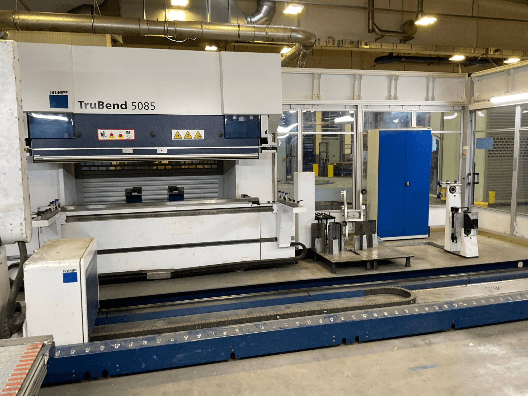 TruBend 5085 van TRUMPF, zijaanzicht van een grote metaalbuigmachine met bedieningspaneel en diverse gereedschappen ernaast.