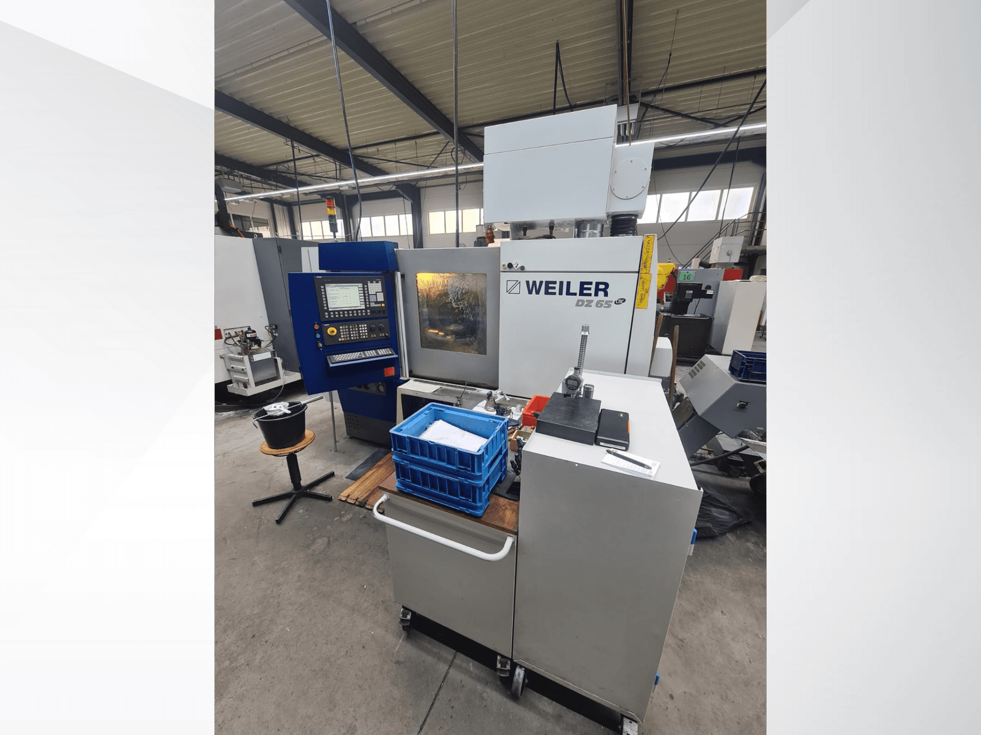 Weiler DZ 65 CNC machine in een werkplaats, vooraanzicht met bedieningspaneel, gereedschappen en blauwe opbergbakken zichtbaar.