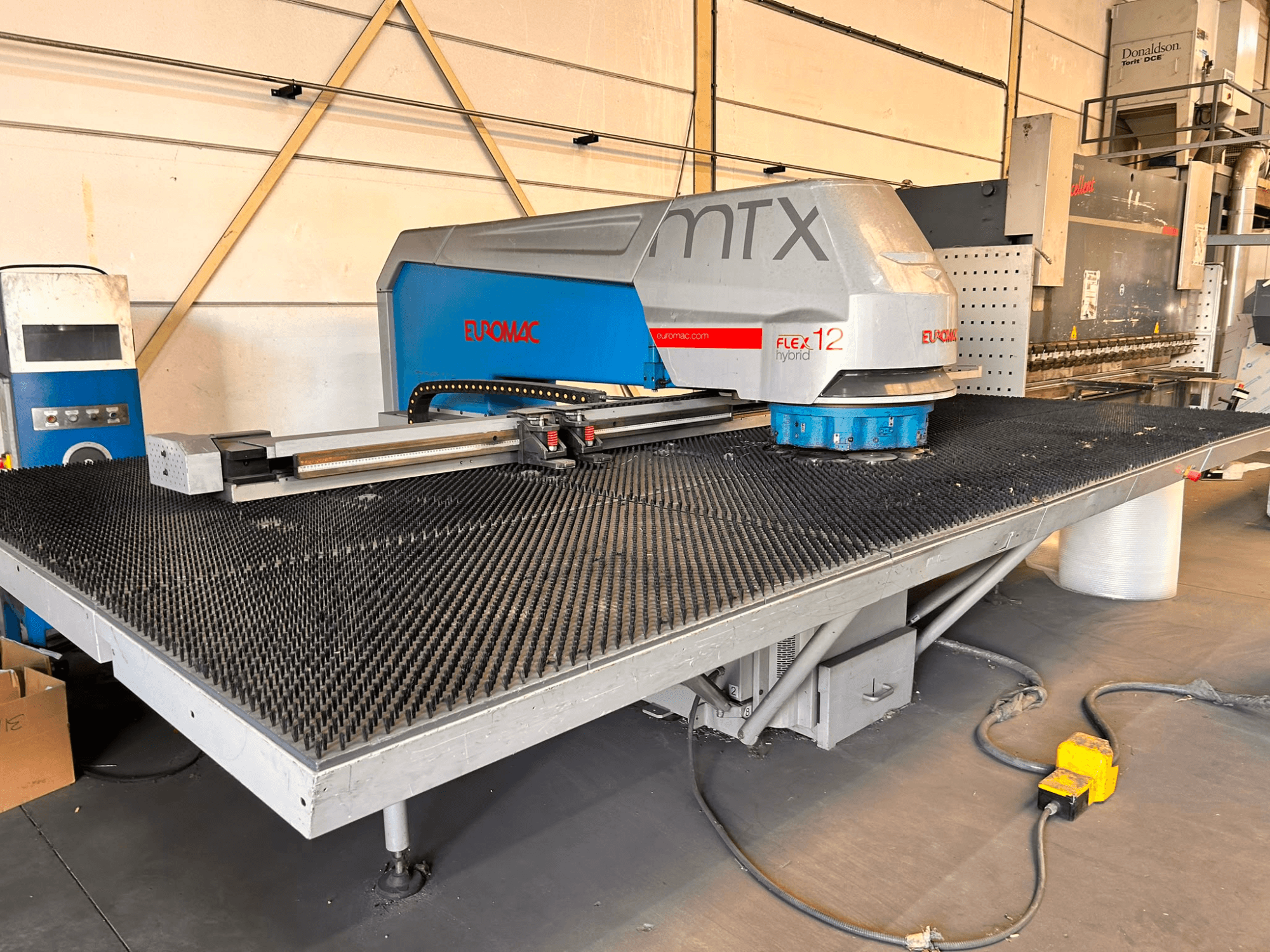 Euromac MTX FLEX 12 CNC-ponsmachine, vooraanzicht, met een grote geperforeerde tafel en bedieningspaneel.