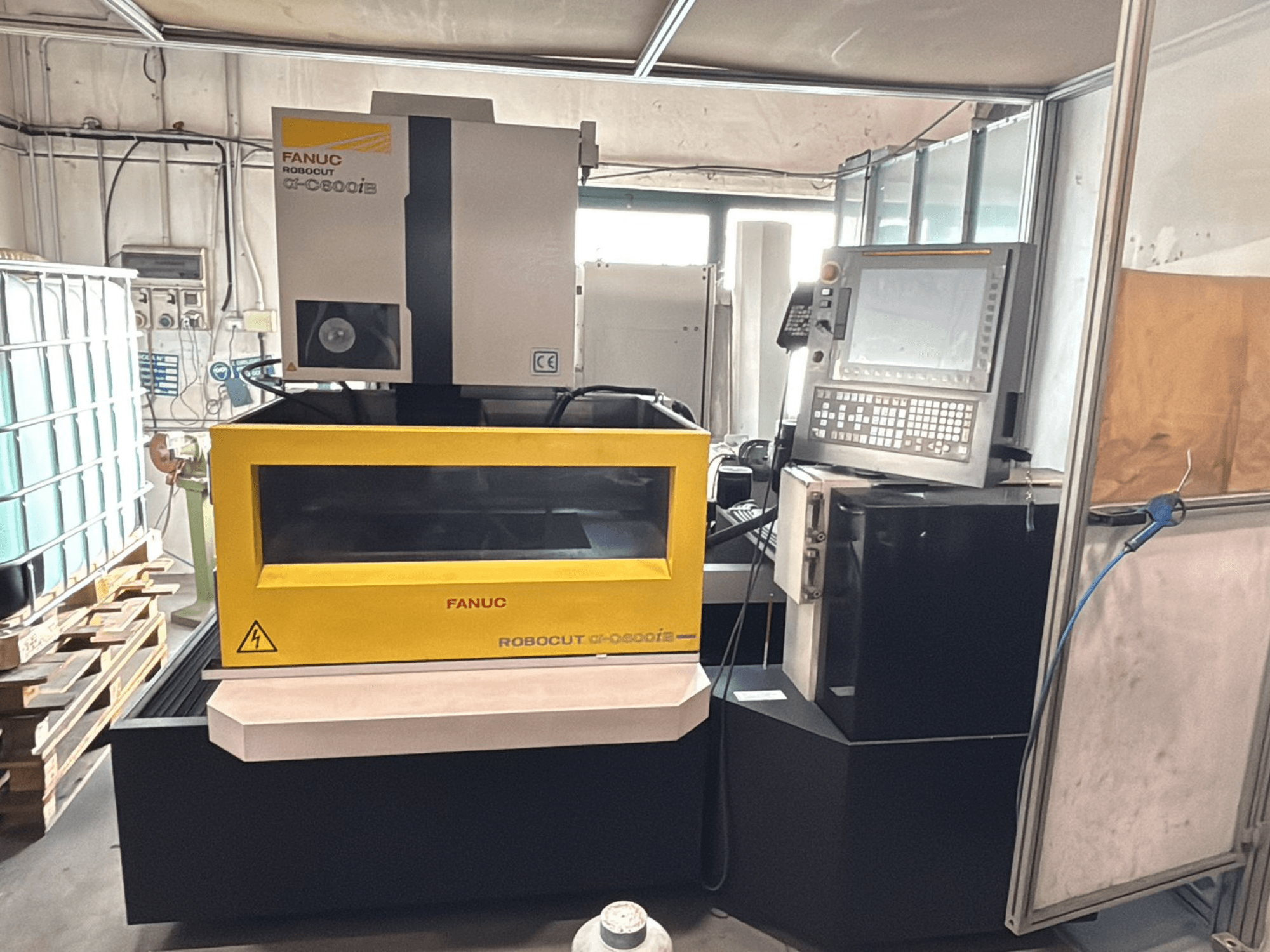 Vooraanzicht van een FANUC Robocut α-0iE CNC machine met gele behuizing, waarop het bedieningspaneel en display te zien zijn.