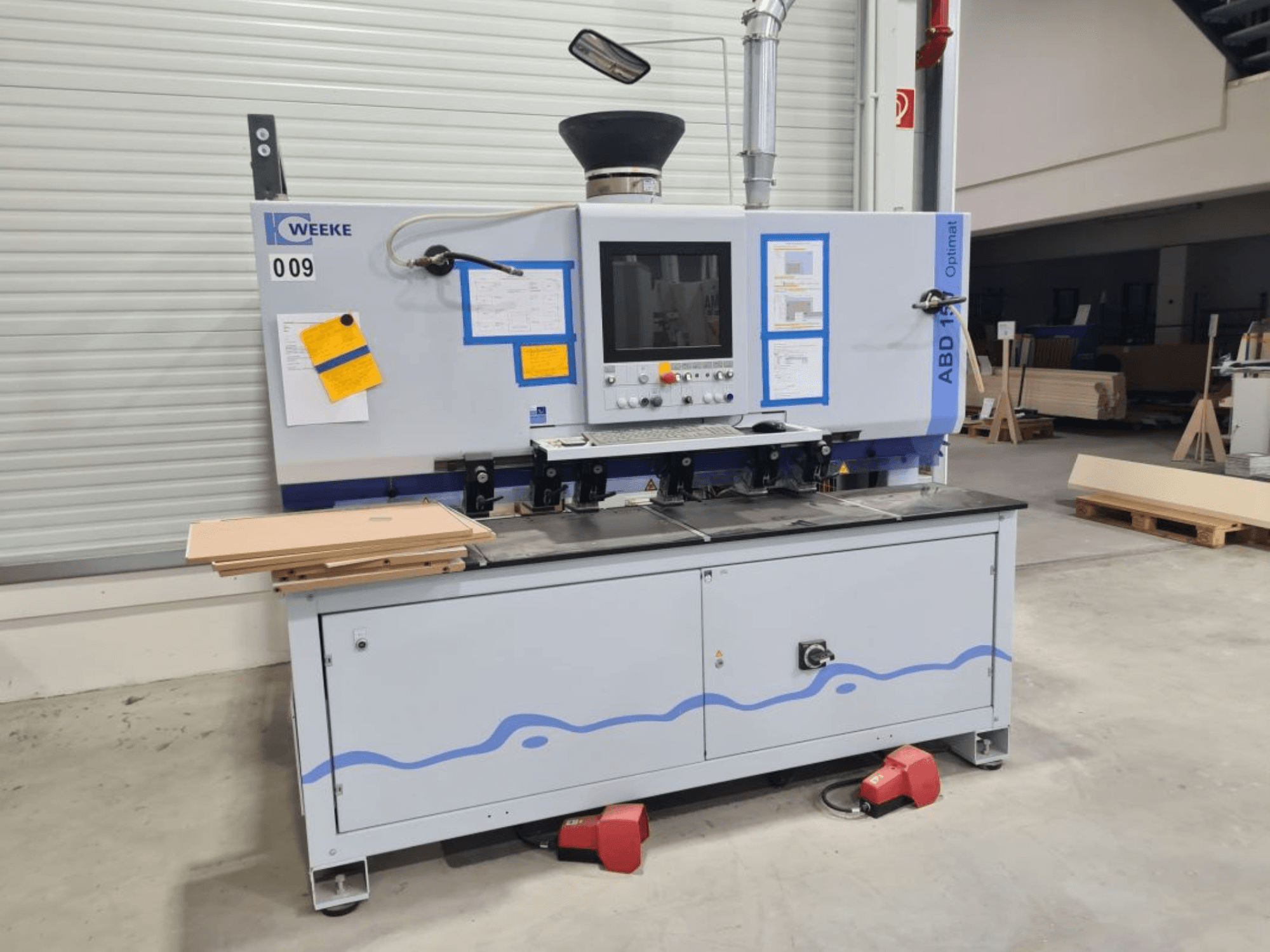 HOMAG WEEKE OPTIMAT ABD150 boormachine met meerdere assen, vooraanzicht, waarop de bedieningselementen en gestapelde houten panelen te zien zijn.