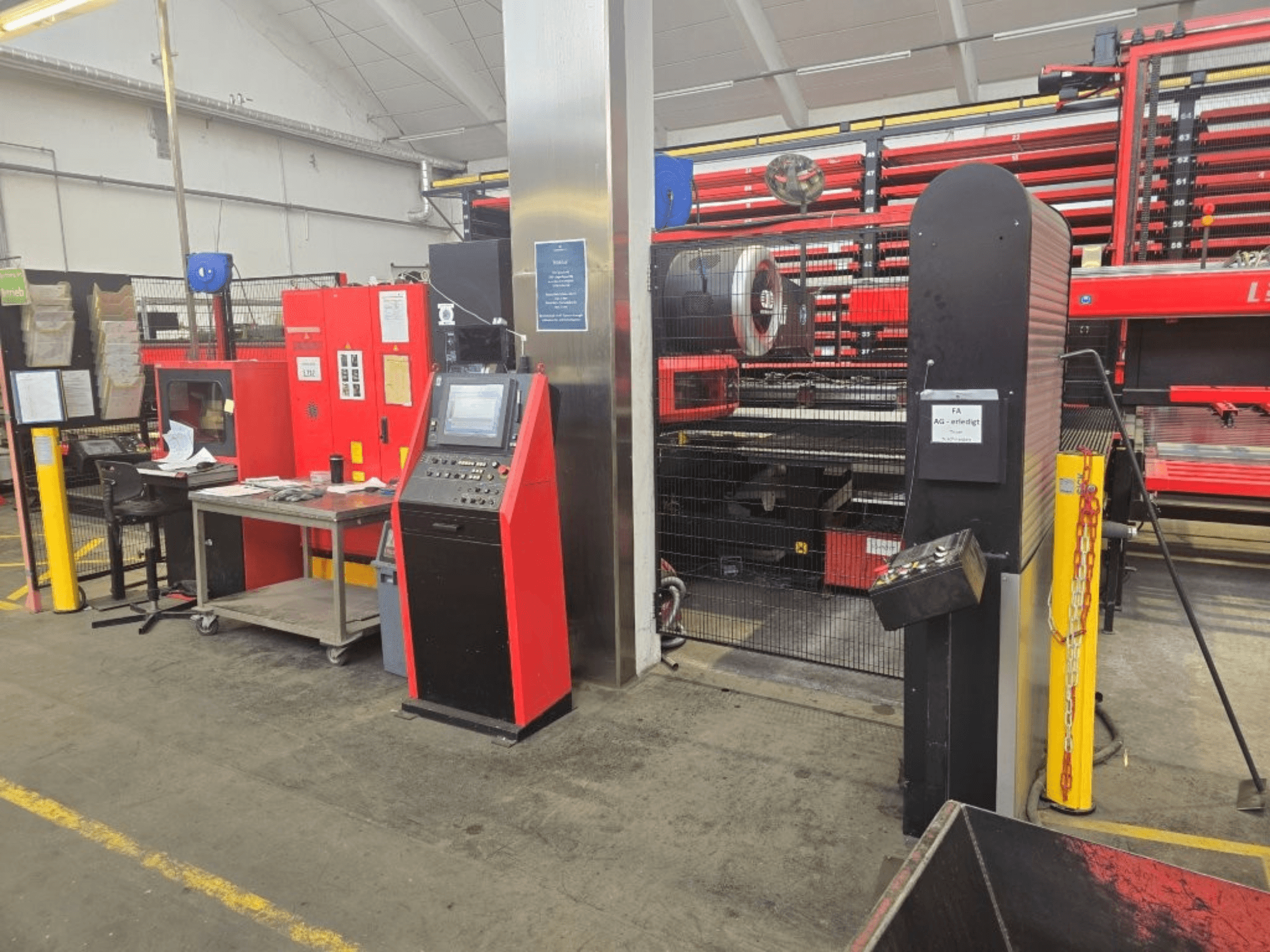Vooraanzicht van de AMADA EMZ 3610 NT CNC-ponsmachine, met bedieningselementen en veiligheidsomhulling in een fabrieksomgeving.