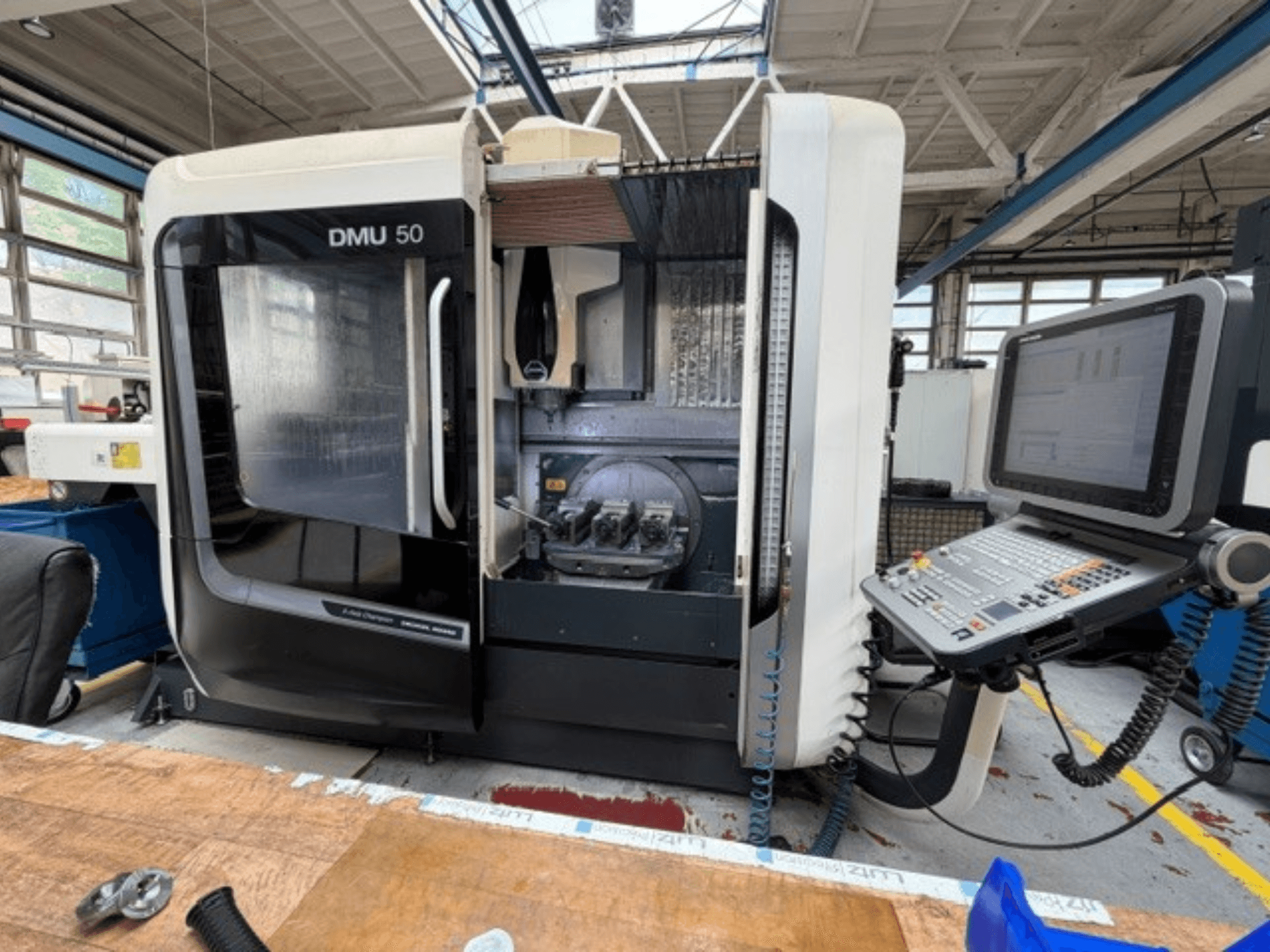 DMG MORI DMU 50 verticaal bewerkingscentrum van de derde generatie, gezien vanaf de voorkant, met geopende deur, zichtbaar CNC-bedieningspaneel en werkruimte binnenin.