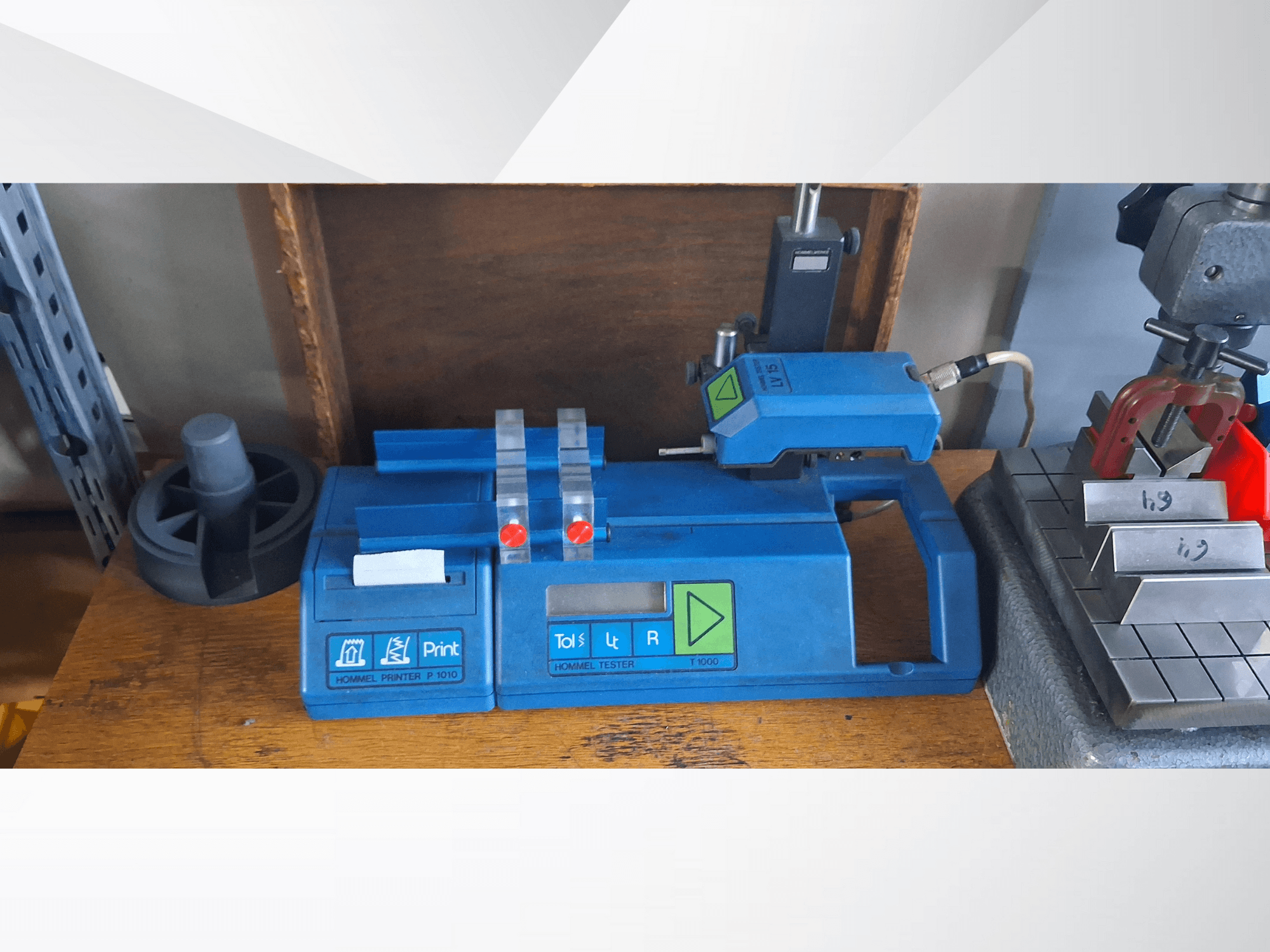 Hommel Printer P 1010 en Tester T1000 in zijaanzicht, met blauwe behuizing, knoppen en rode indicators, op een werkbank.