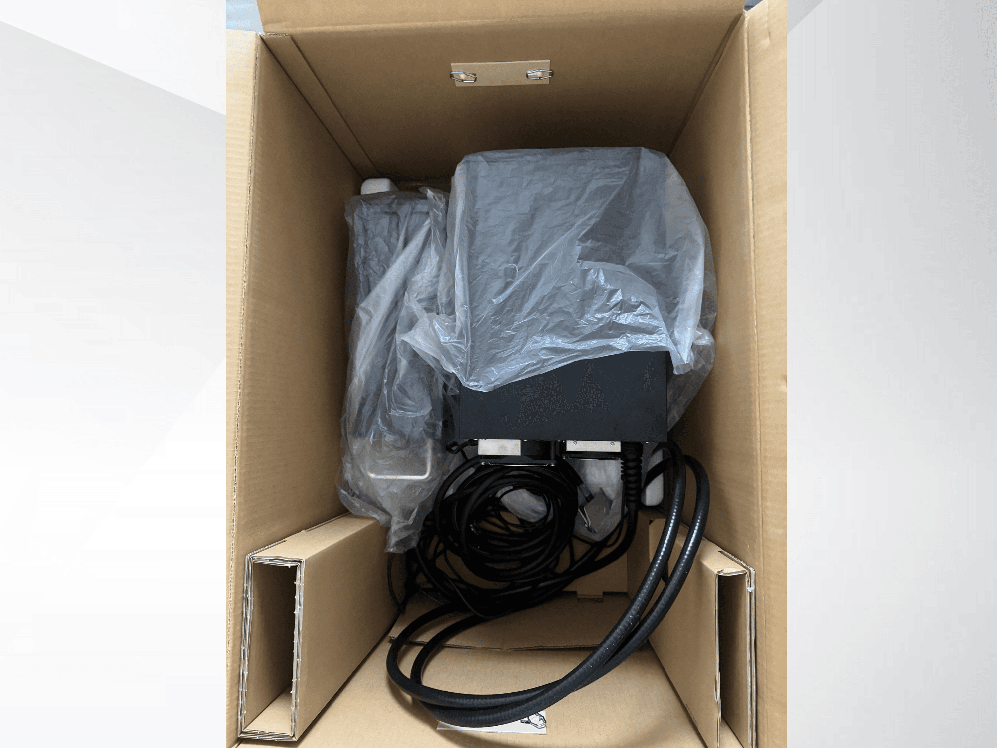 KEYENCE MD-X2500A lasermarkeermachine in een kartonnen doos, gedeeltelijk bedekt met plastic, waarbij de kabels en onderdelen zichtbaar zijn.