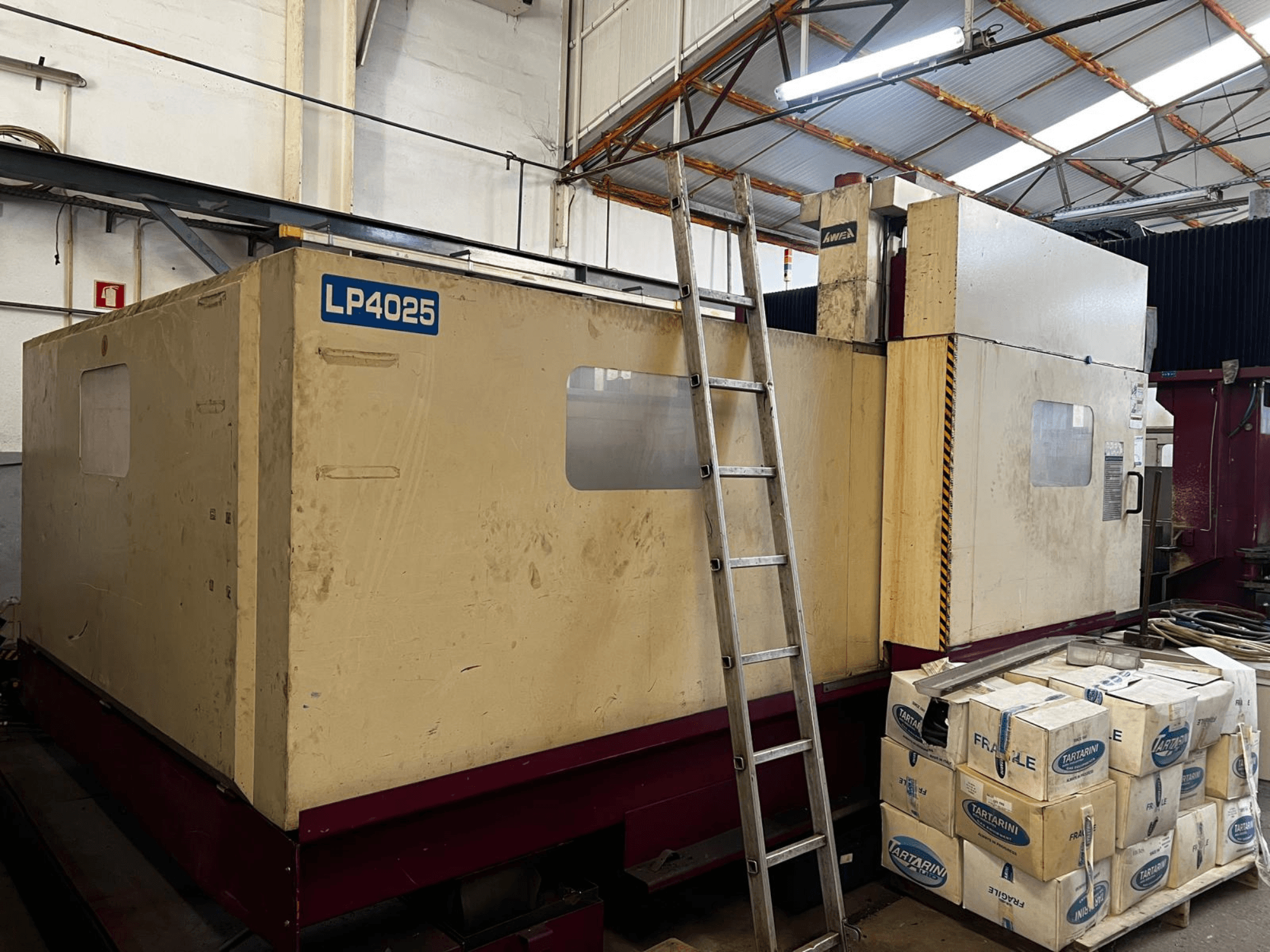 AWEA LP4025-portalfreesmachine in een industriële omgeving, zijaanzicht met de grote machines en opslagkisten.