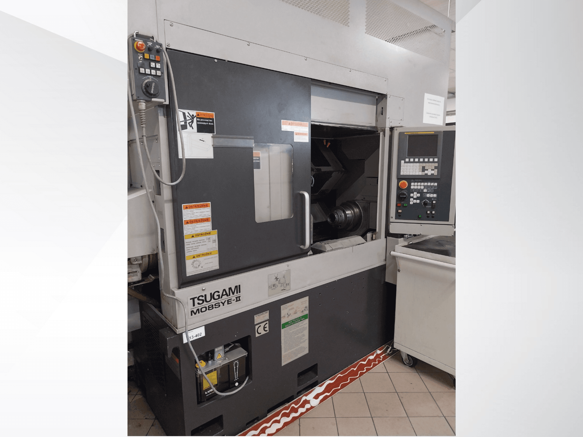 Tsugami M08SY-II CNC draaibank, vooraanzicht, met bedieningspaneel, spindel en laadgebied. Met veiligheidsopmerkingen en merklabel.