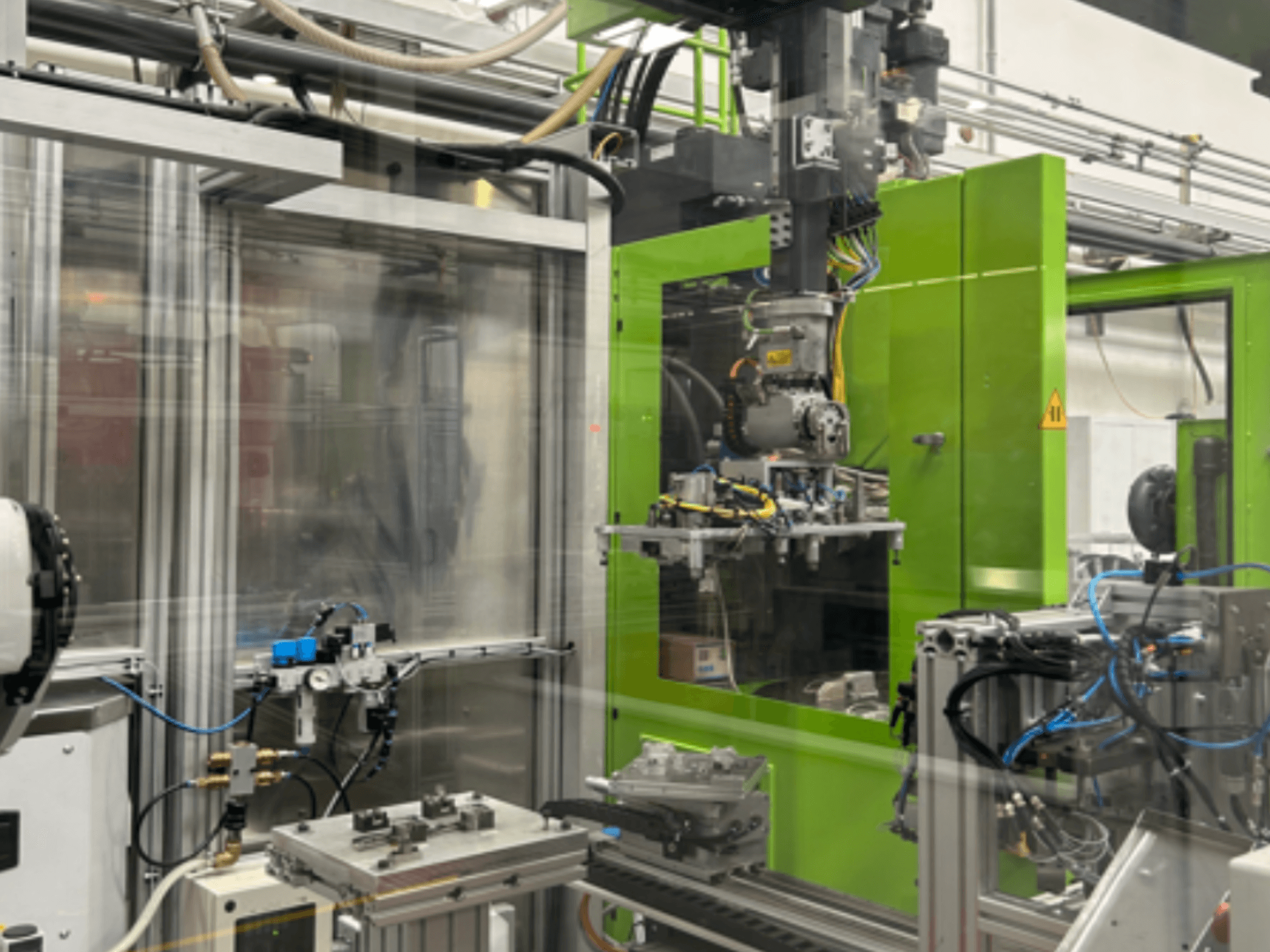 Industriële robotmachines in groene behuizing, met mechanische onderdelen en leidingen, gezien vanaf de voorkant.