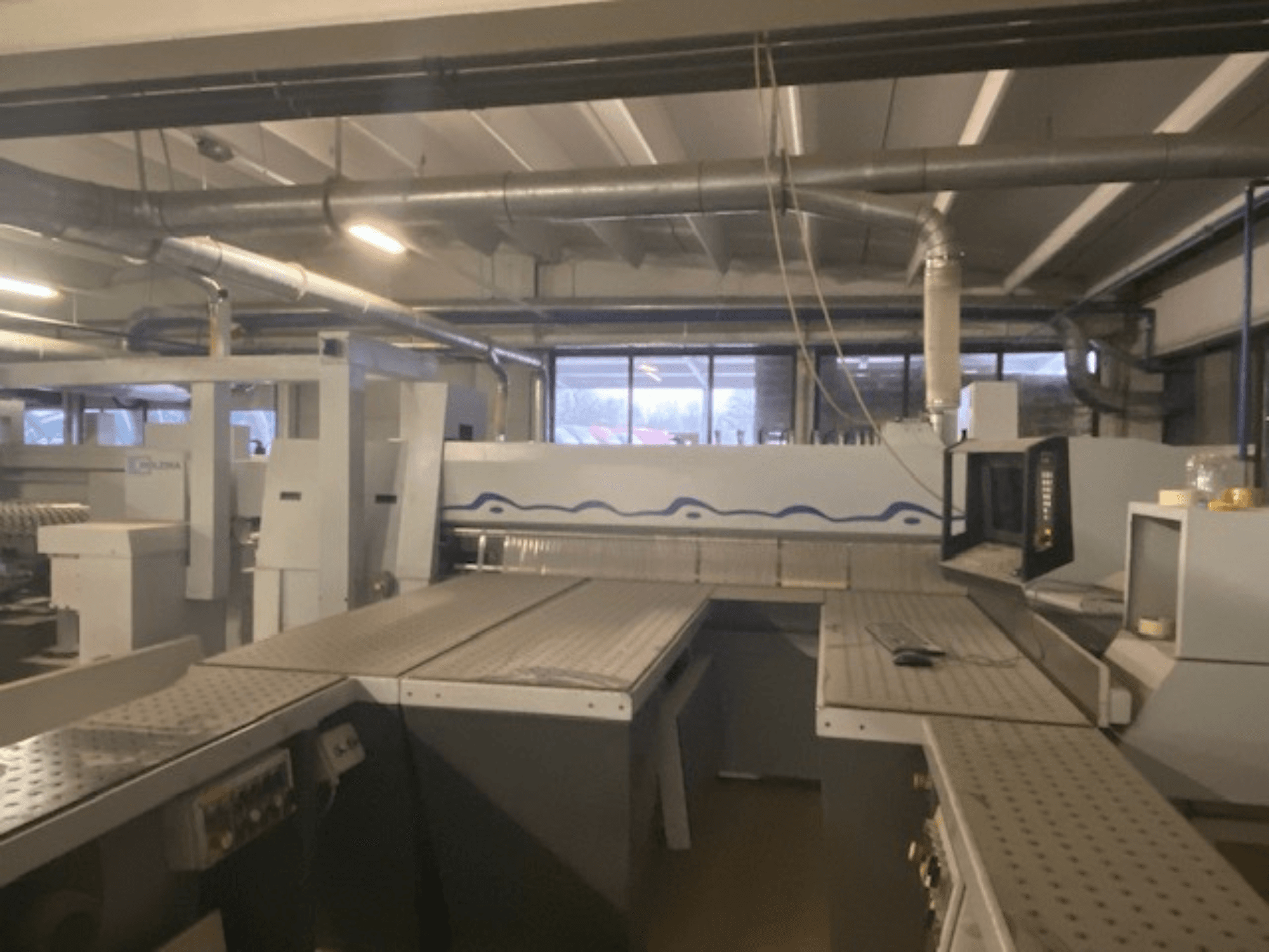 Industriële werkruimte met een machineopstelling en bedieningspaneel, gezien vanuit een verhoogde vooraanzicht.