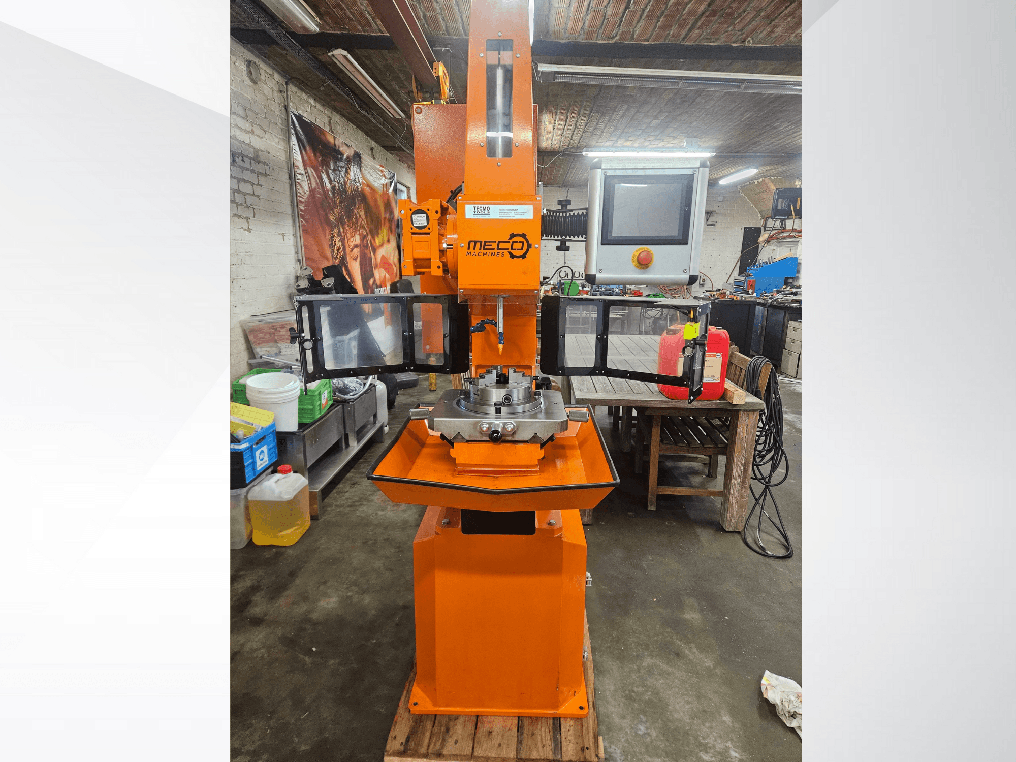 MEC oranje freesmachine, vooraanzicht, met bedieningspaneel en werktafel, opgesteld in een werkplaats met gereedschap en materialen.