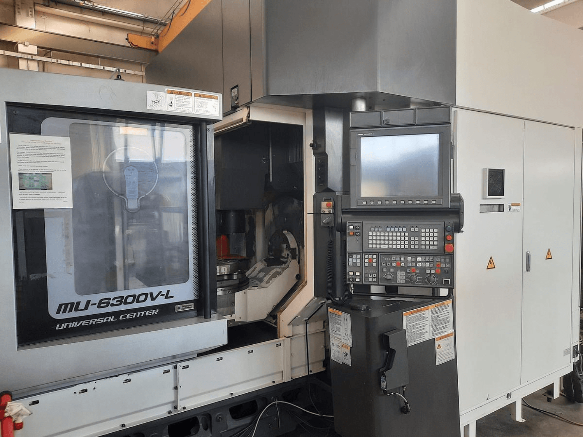 MU-6300V-L Universal Center machine getoond vanaf de voorkant, met bedieningspaneel, scherm en bedieningsinstructies zichtbaar.