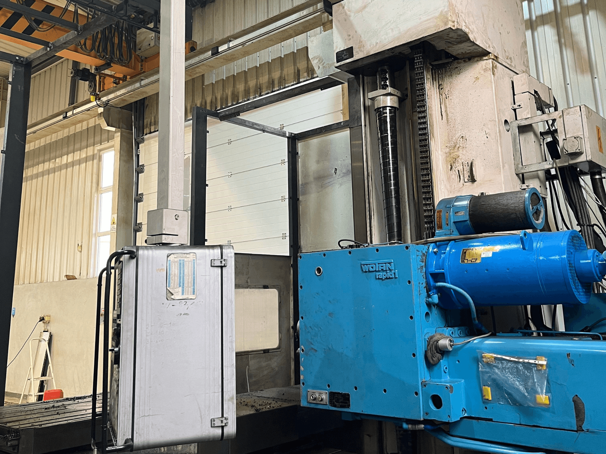 WOTAN Rapid 1-boormachine in blauw, zijaanzicht, met zicht op de motor, de bedieningselementen en de verticale kolom in een werkplaatsomgeving.