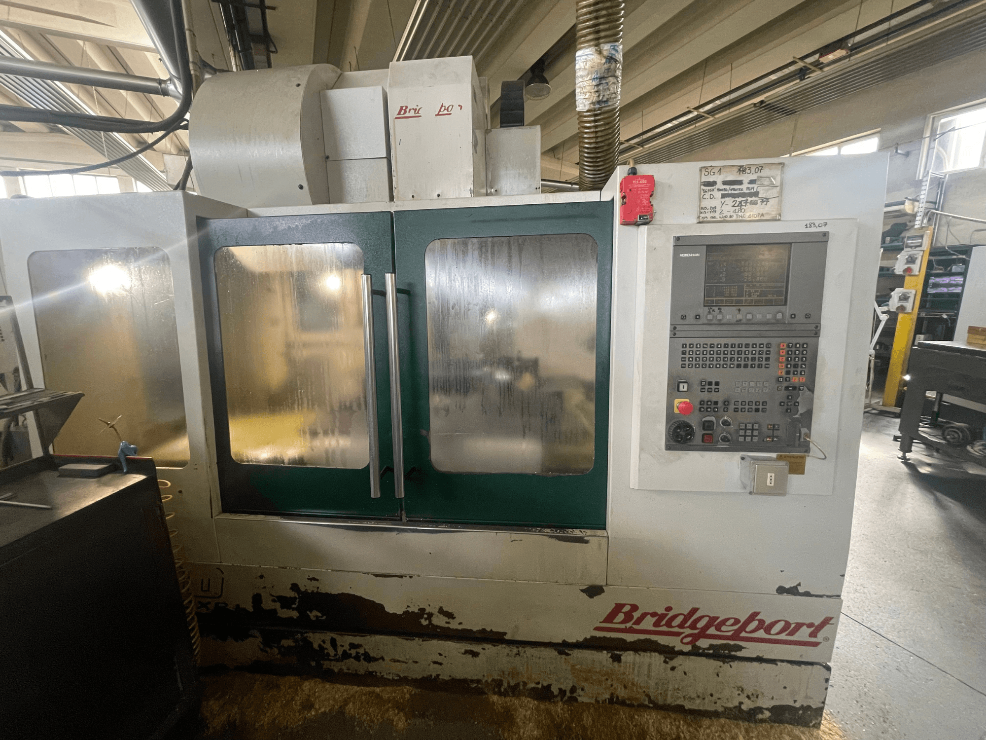 Verticaal bewerkingscentrum Bridgeport VMC 1000/30, vooraanzicht met bedieningspaneel, met zichtbare slijtage aan de buitenkant en groene deuren.