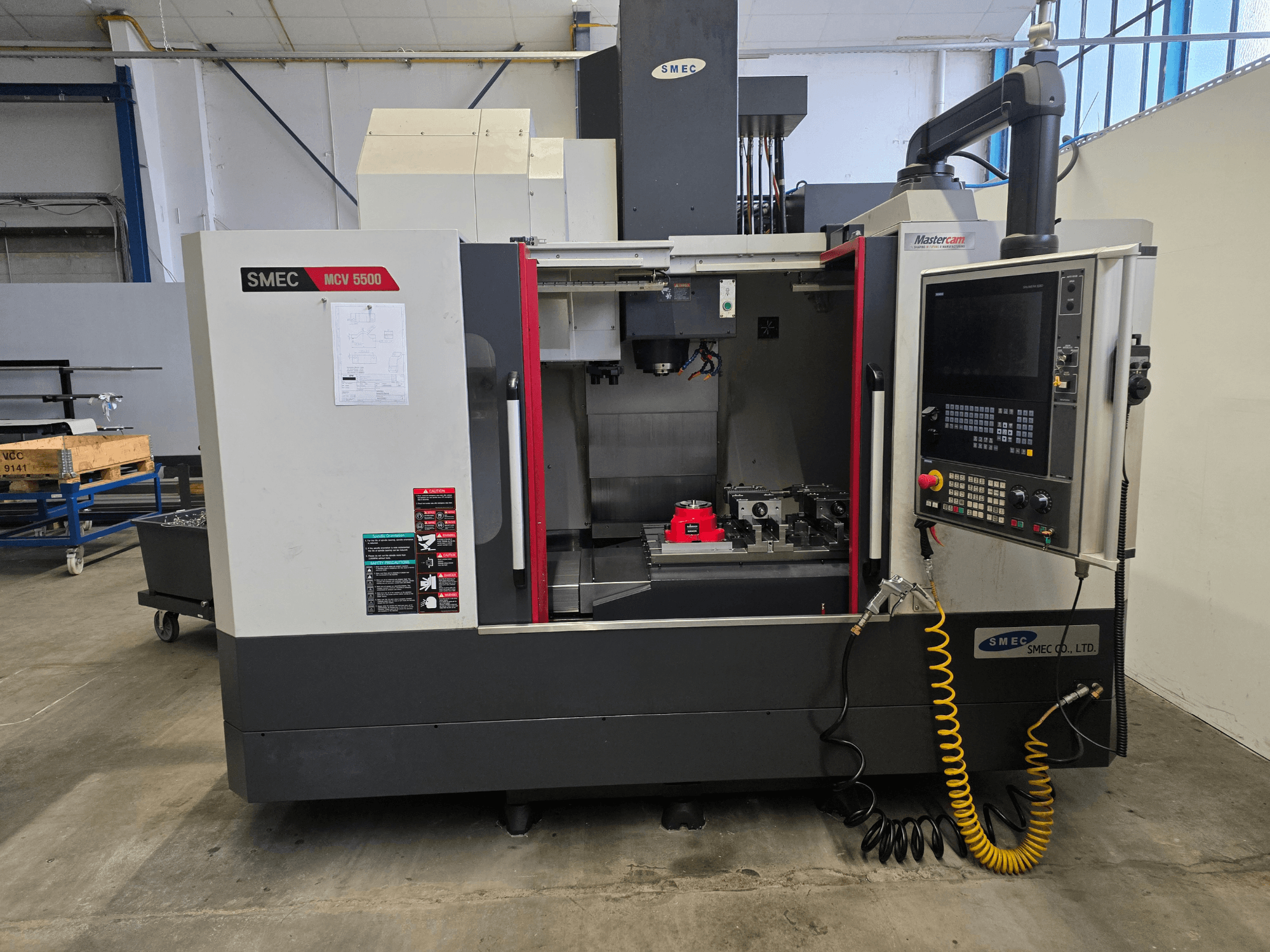 SMEC MCV 5500 verticaal bewerkingscentrum, vooraanzicht, met weergave van het bedieningspaneel en het binnenwerk van de machine met gereedschappen.