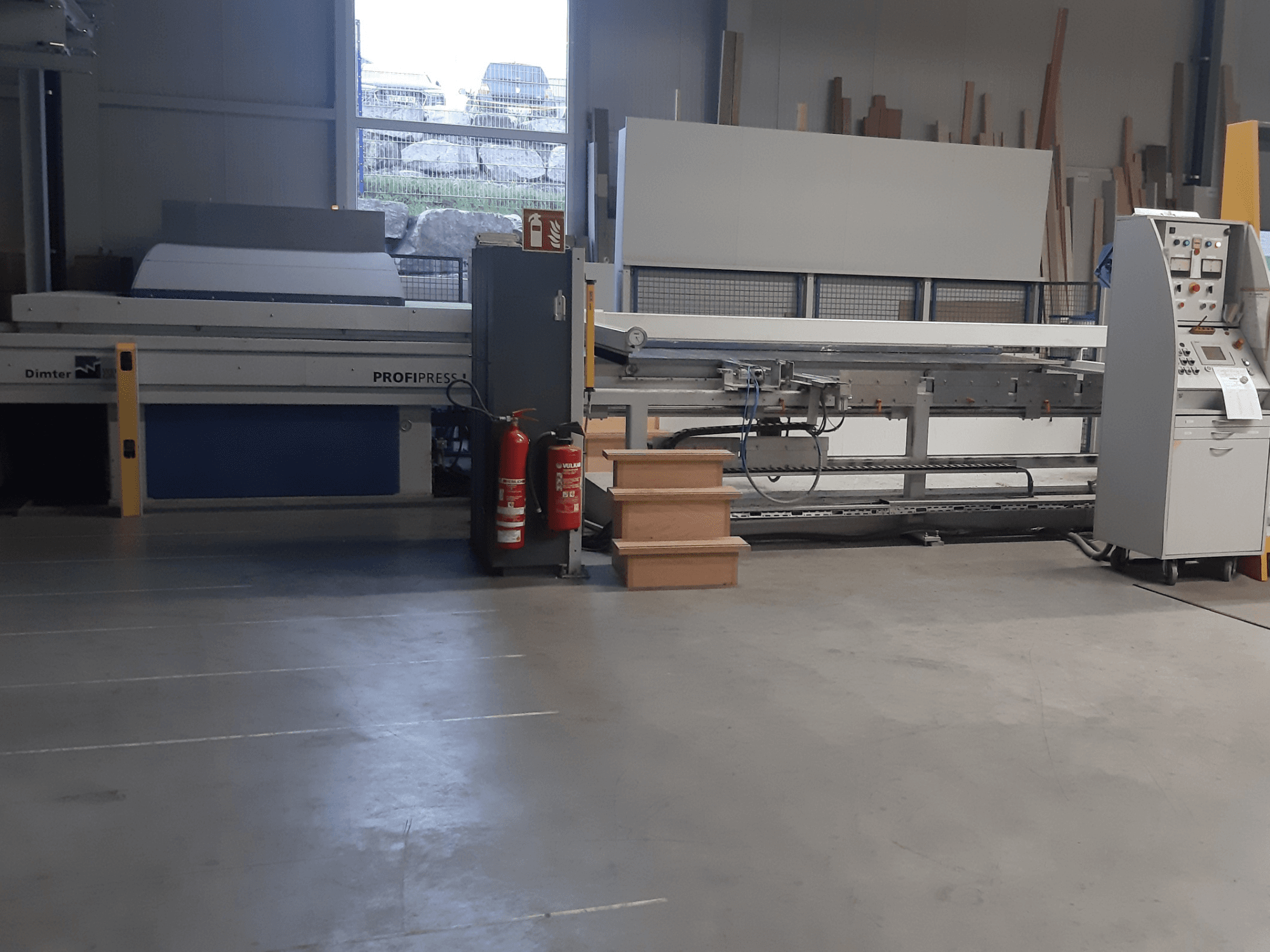 Dimter ProfiPress-machine in een werkplaats, gezien vanaf de voorkant, met bedieningspaneel en brandblussers vlakbij.