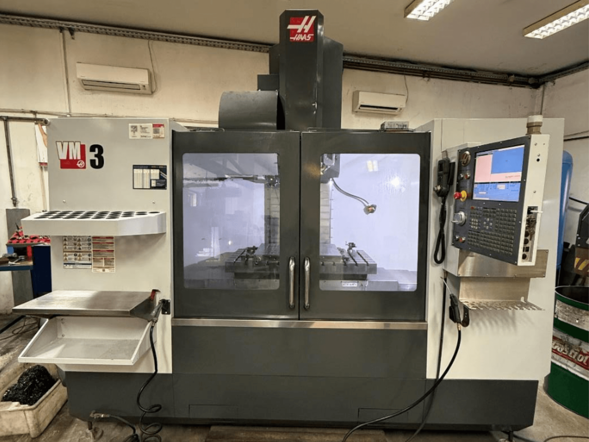 Verticaal bewerkingscentrum Haas VM-3 in vooraanzicht, met een groot bedieningspaneel en een zichtbaar werkgebied met gereedschappen.