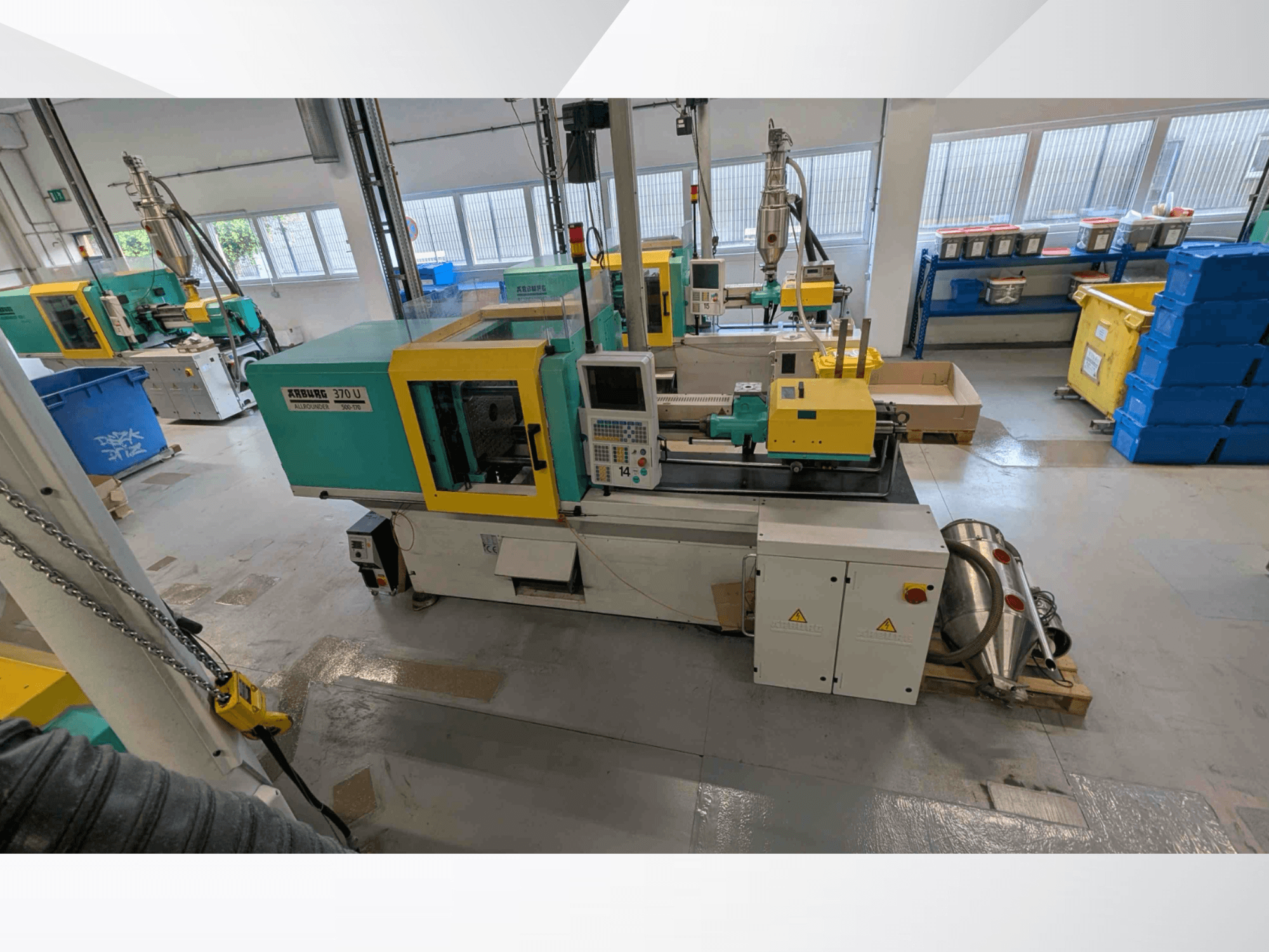 Vooraanzicht van een Arburg 370 U 500-170 verticale spuitgietmachine met bedieningspaneel en machineonderdelen in een werkplaats.