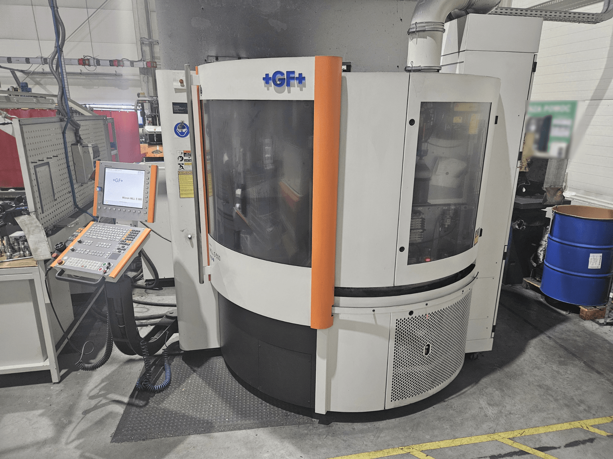 GF Machining Solutions bewerkingsmachine met bedieningspaneel, vooraanzicht; heeft transparant paneel, oranje accenten en industriële instelling.