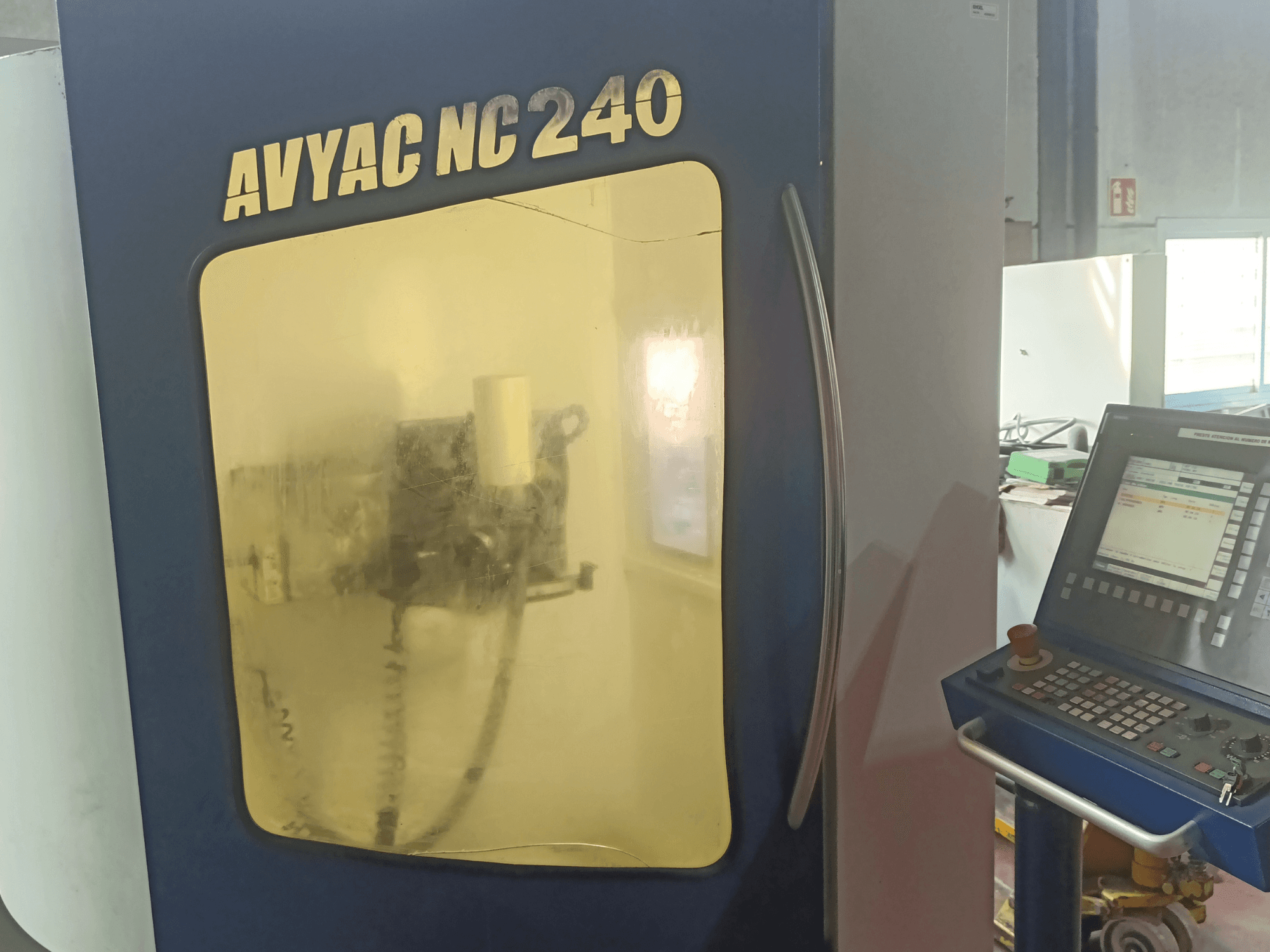 AVYAC NC240 rondslijpmachine, zijaanzicht met bedieningspaneel en gedeeltelijk zichtbaar slijpgedeelte door het venster.