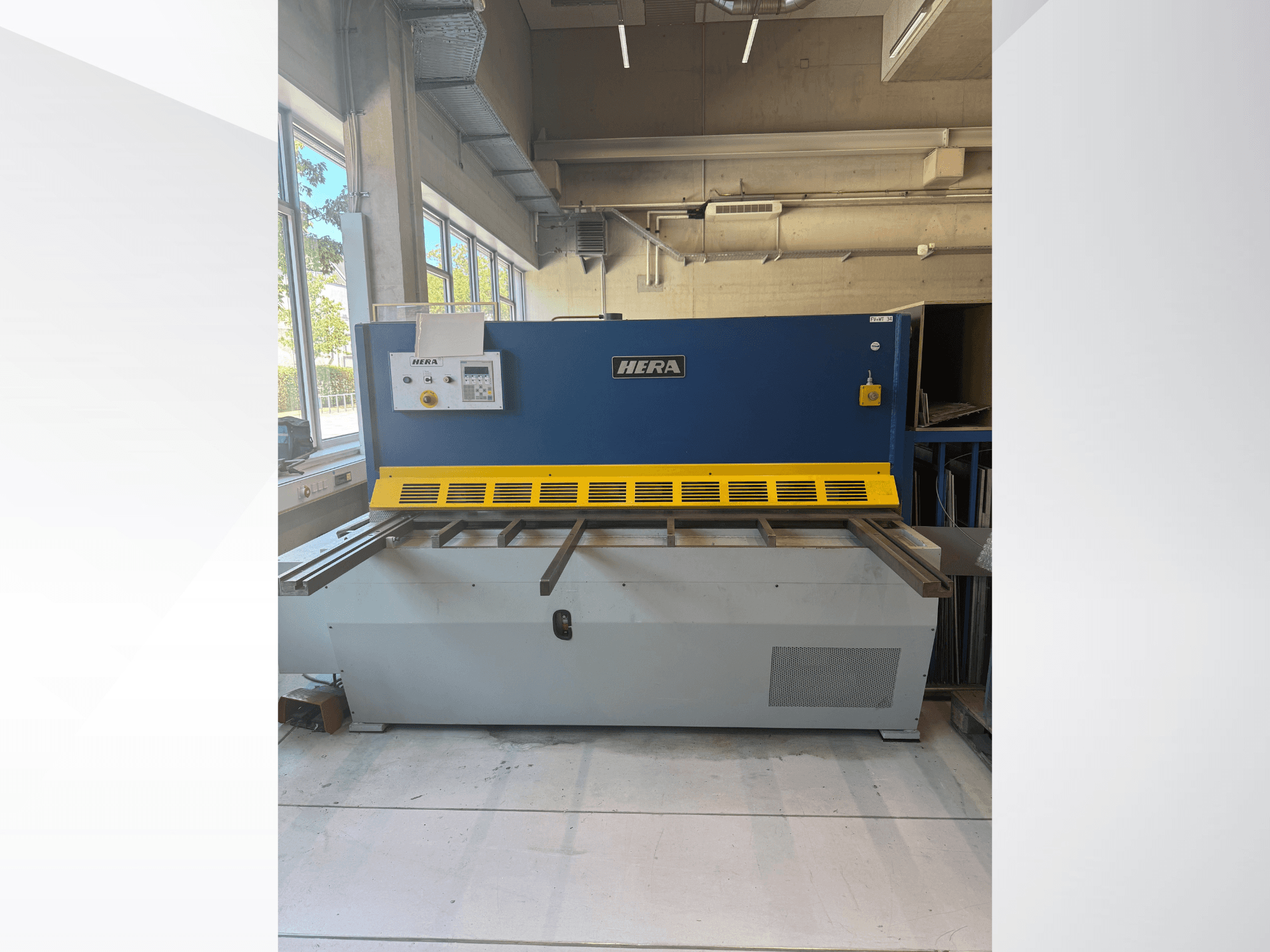 HERA TS 2000x6 hydraulische knipmachine in vooraanzicht, uitgevoerd in blauw en geel, met bedieningspaneel en kniptafel.
