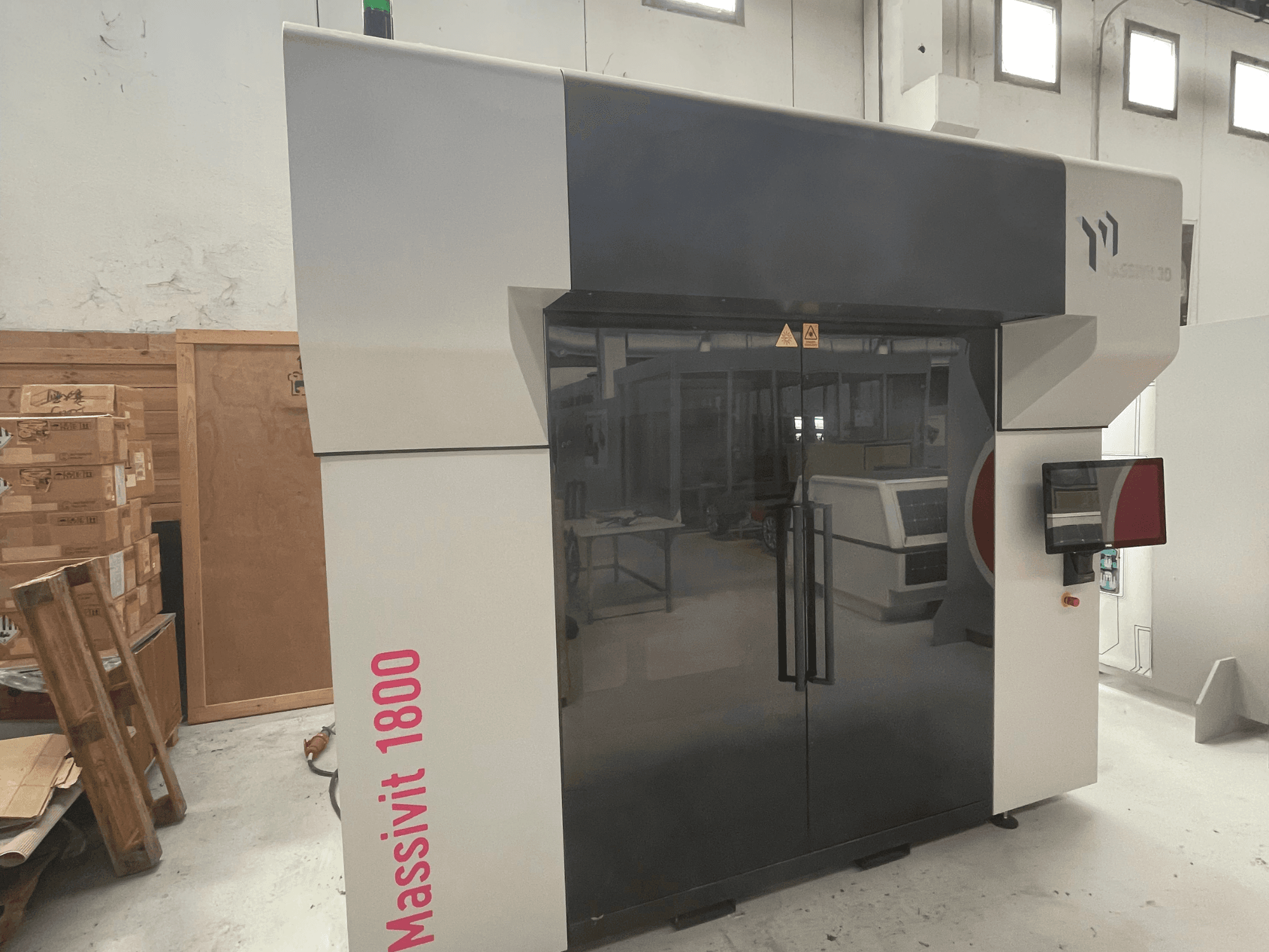MASSIVIT Massivit 1800 3D-printer voor kunststof, afgebeeld in zijaanzicht, met een touchscreen en een strak zwart-wit ontwerp.