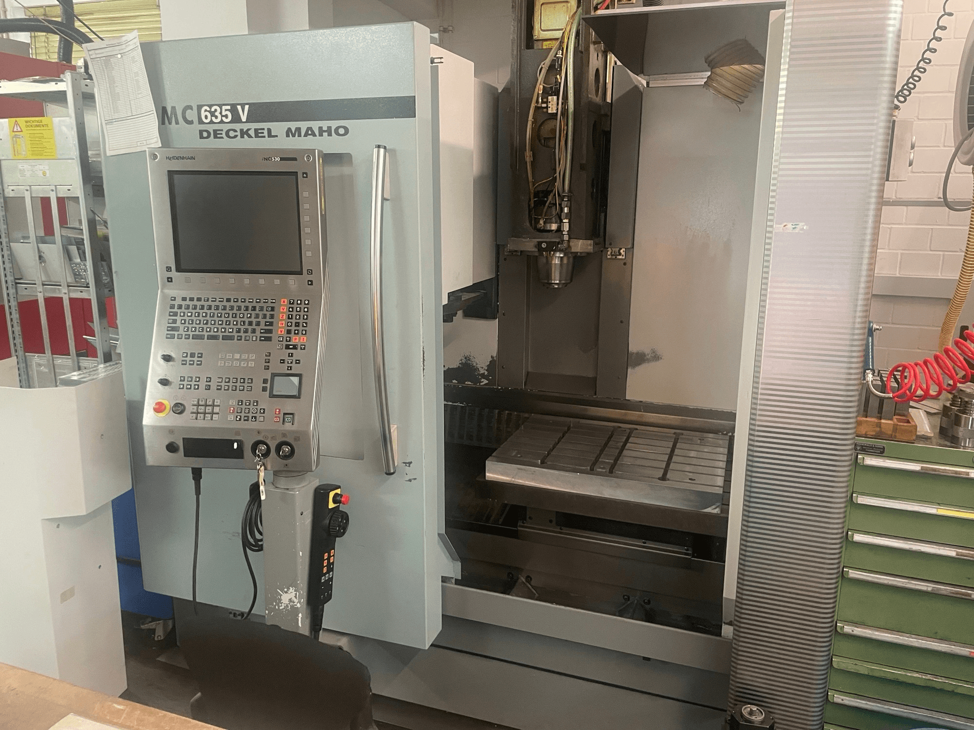 Vooraanzicht van het verticale bewerkingscentrum DECKEL MAHO DMC 635 V met bedieningspaneel en open werkruimte, waarop de gereedschapskop en het werkbed te zien zijn.