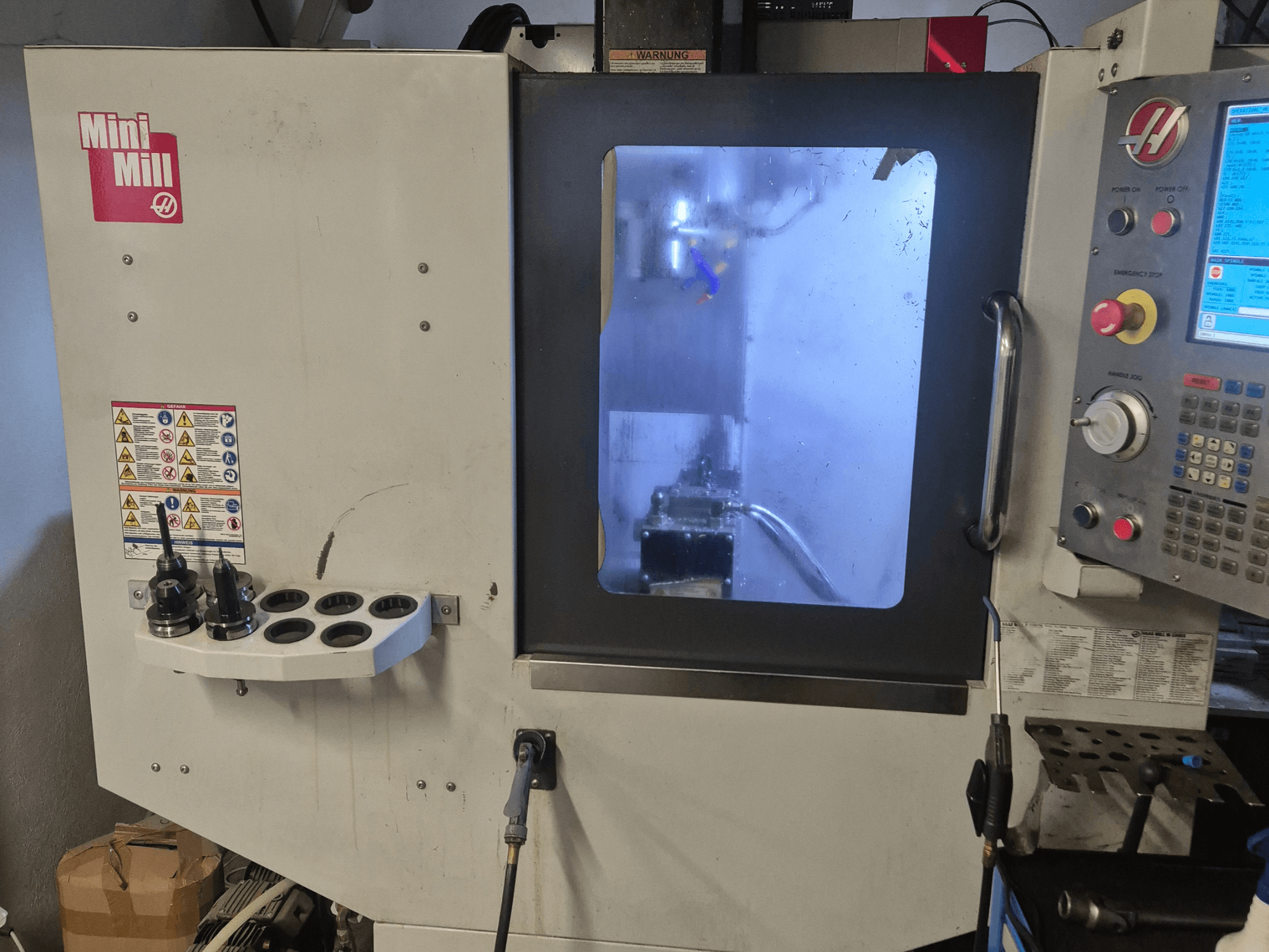 Vooraanzicht van HAAS Mini Mill, met het bedieningspaneel, gereedschapshouders en zicht op het bewerkingsgebied met koelvloeistof.