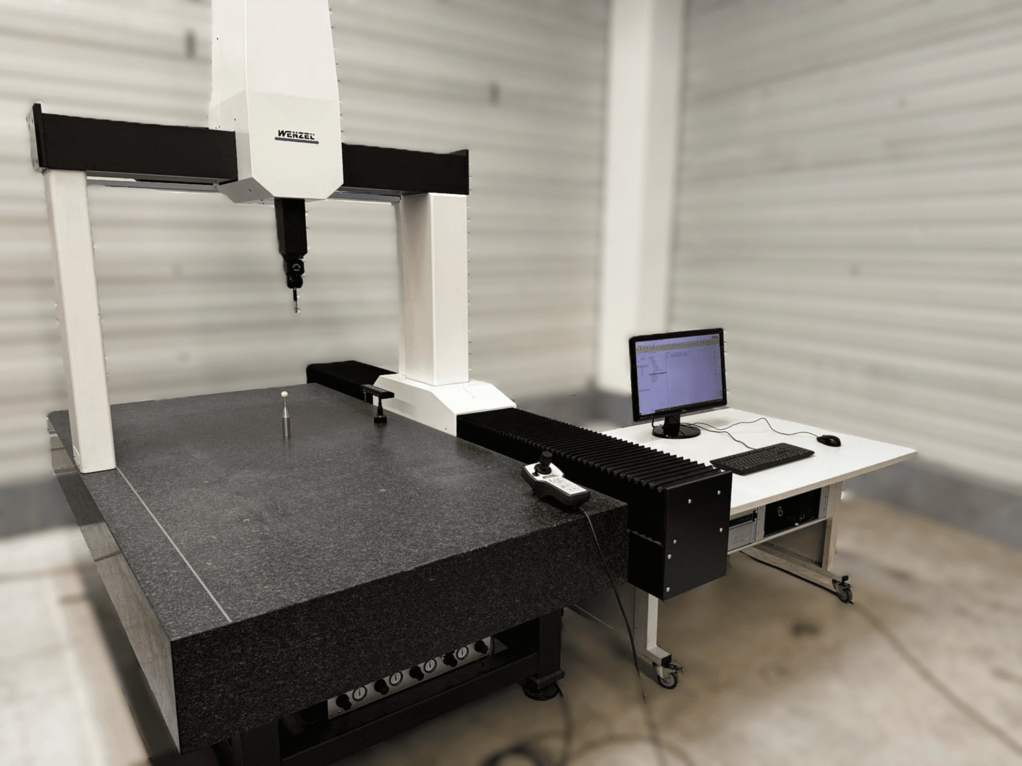 Wenzel XO 87 CMM in vooraanzicht, met een meettaster en een granieten tafel met een computeropstelling ernaast.