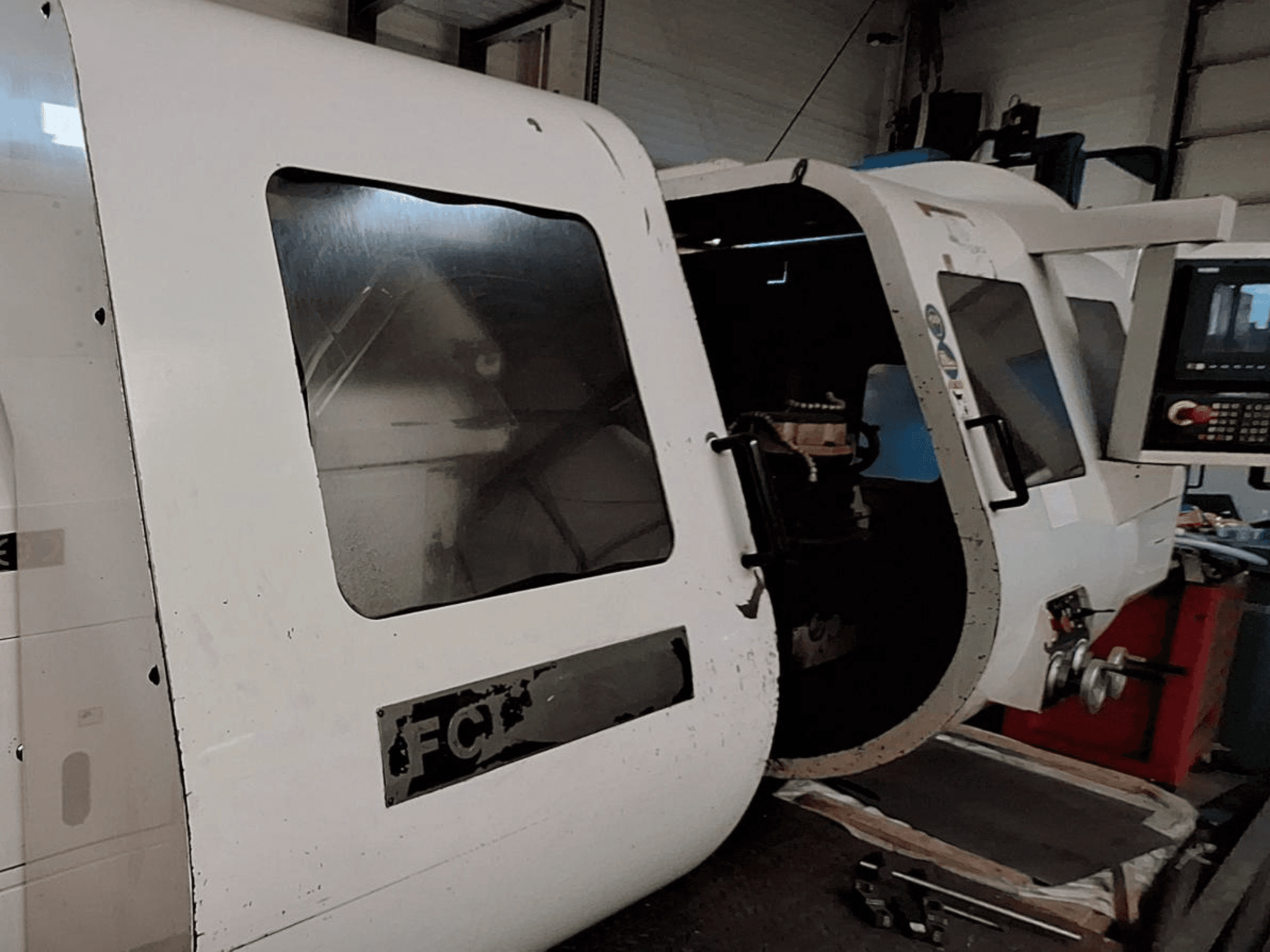 Witte CNC machine met zichtbaar bedieningspaneel en open deur, waarop de onderdelen aan de binnenkant te zien zijn; vooraanzicht. Merk: FCT.