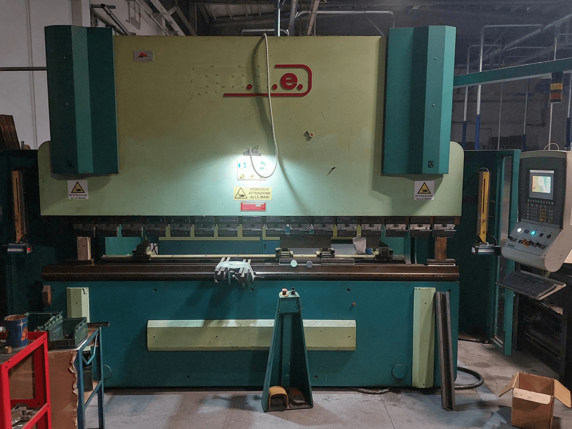 Vooraanzicht van de Gade PS-C 3120 kantpers, met bedieningspaneel, veiligheidsborden en werkruimte met gereedschap en materialen.