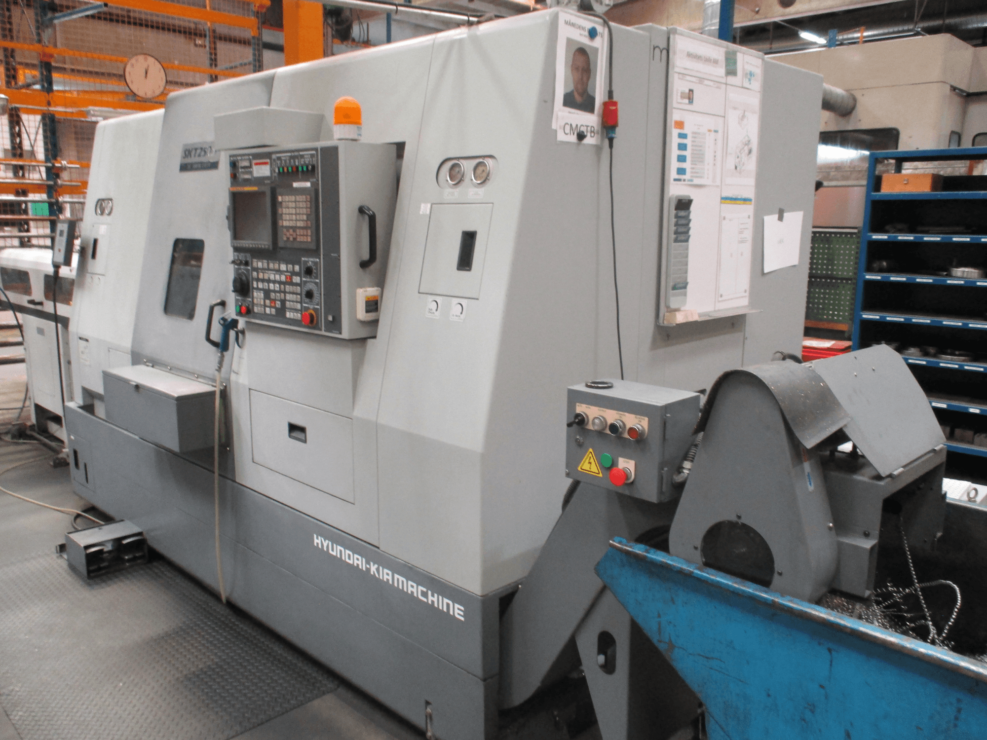 Vooraanzicht van de horizontale draaimachine HYUNDAI KIA SKT250SY; met bedieningspaneel, spaanderbak en veiligheidsborden.