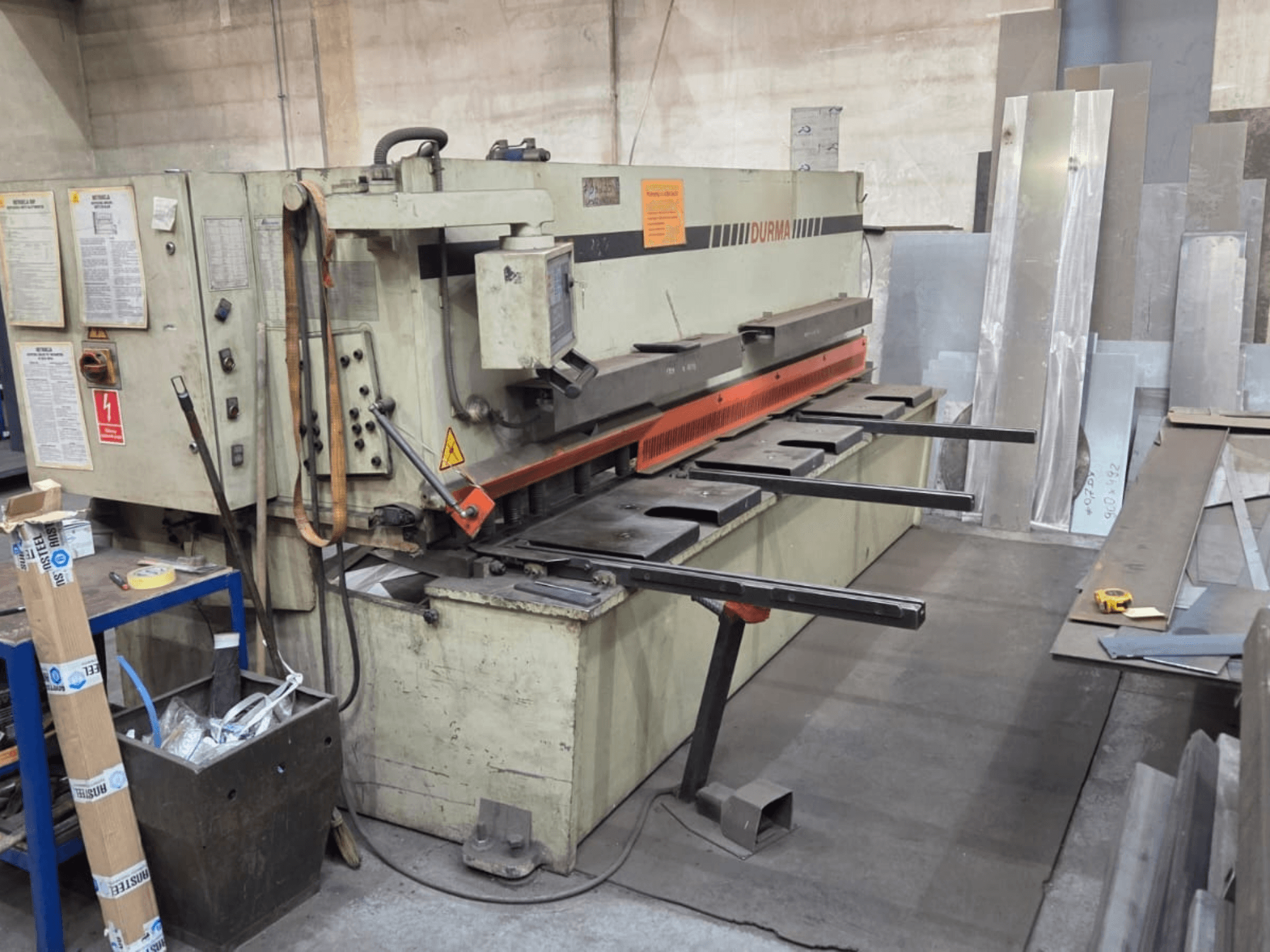 Hydraulische schaarmachine Durma SB 3060, vooraanzicht, met bedieningselementen, snijblad en metalen platen in de werkruimte.